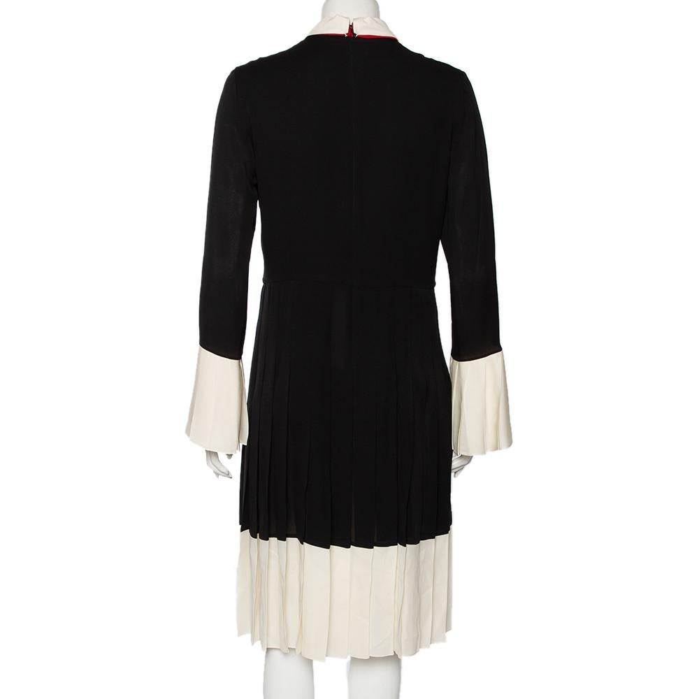 Gucci's vintage aesthetic blended with classy, contemporary fashion is visible through the masterful creation of this dress. Overlaid with black silk fabric, this dress is enriched with a red georgette bow on the front, pleated formations, and clean