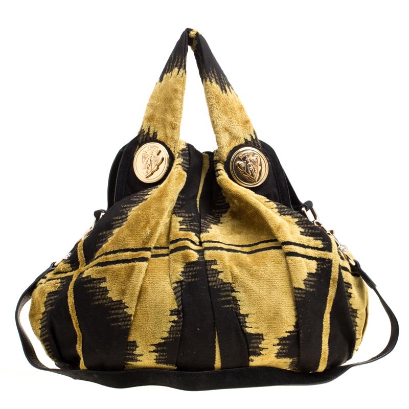 This Gucci hobo is built for everyday use. Crafted from black and yellow fabric, it has a shoulder strap and two handles for you to parade it. The nylon insides are spacious and the hobo is complete with the signature emblems on the