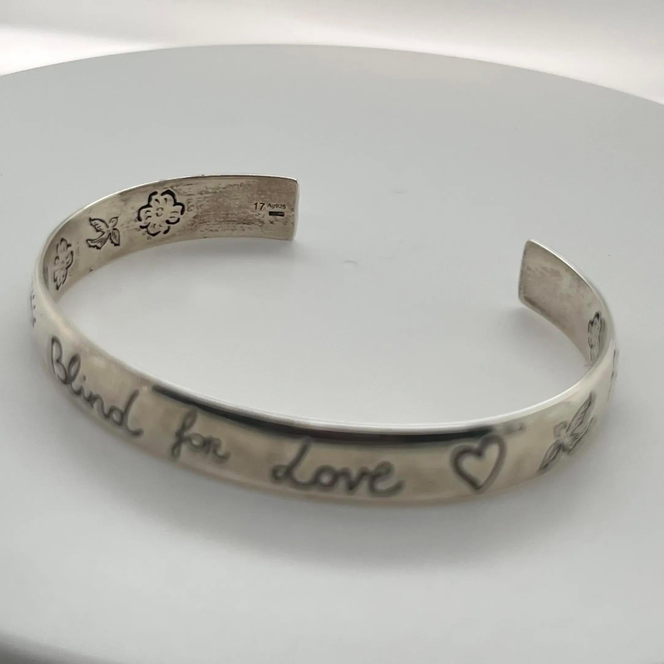 This cuff bracelet is designed in 925 sterling silver featuring engraved symbolic Gucci motifs, including the eye, hearts, birds, flowers, and the phrase 