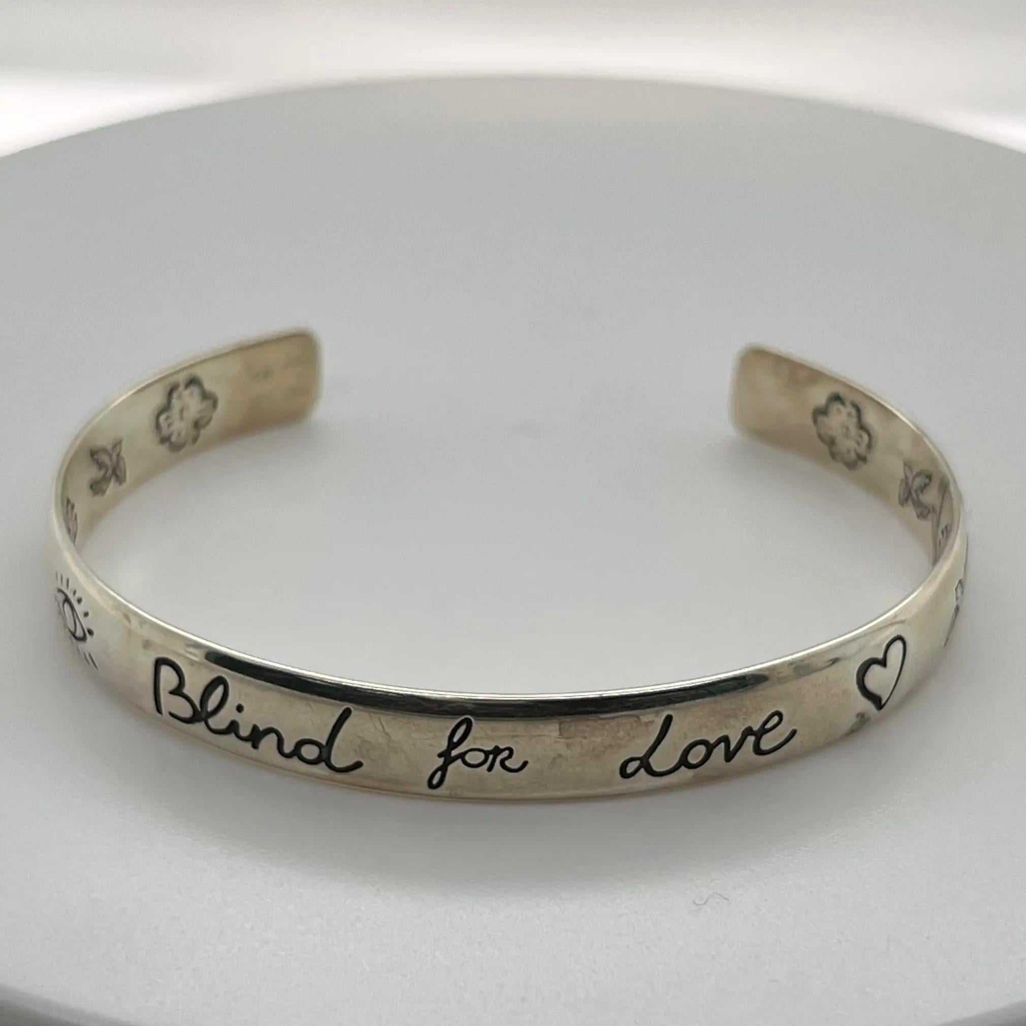 Ce bracelet manchette est conçu en argent sterling 925 et présente des motifs symboliques gravés de Gucci, notamment l'œil, des cœurs, des oiseaux, des fleurs et la phrase 