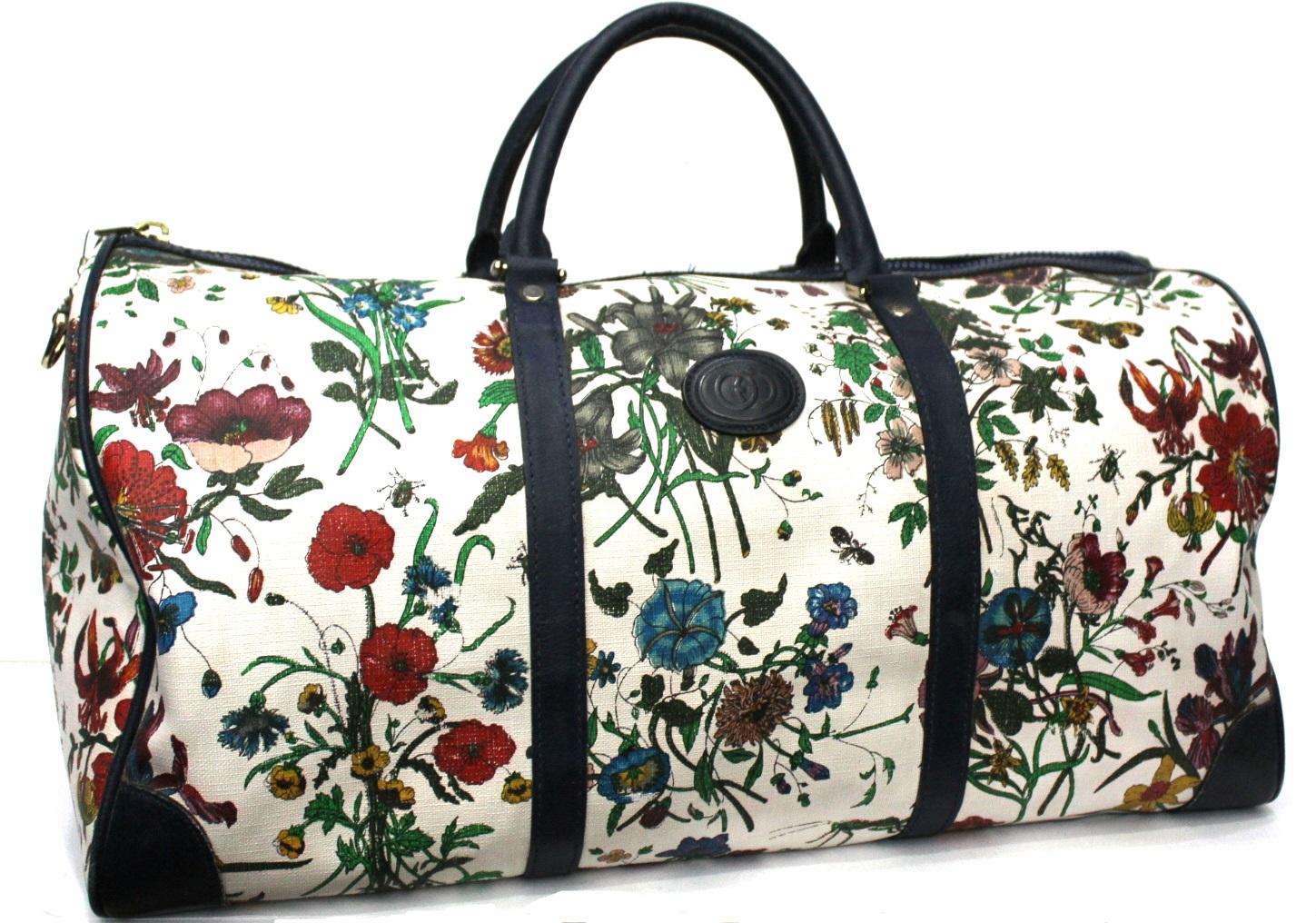 Duffel bag from the Gucci Flora line. Currently the Flora line has returned to the Gucci collections. Made of white canvas with flower print. Blue leather handles and details. Zip closure, very large inside. Missing shoulder strap.