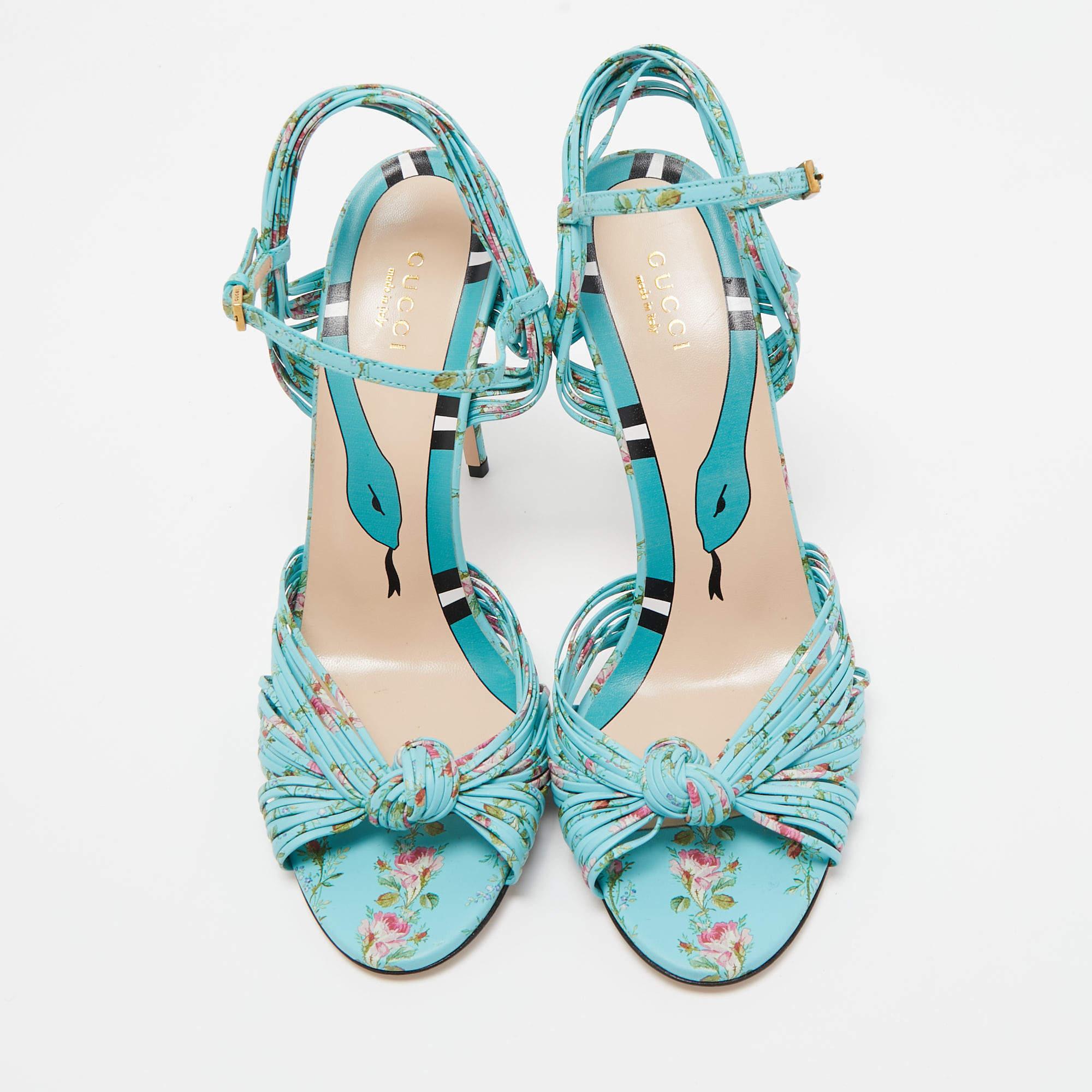 The Gucci Allie sandals are a stunning blend of luxury and style. These open-toe sandals feature a vibrant blue leather exterior adorned with a delicate floral print, a high heel, and an ankle strap for a secure and elegant fit. Perfect for adding a