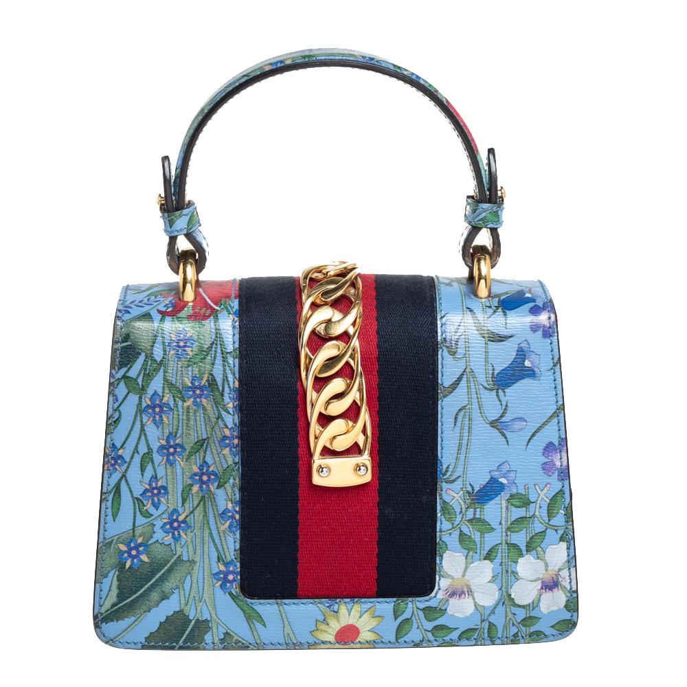 From the house of Gucci comes this gorgeous Sylvie bag that will perfectly complement all your outfits. It has been luxuriously crafted from floral printed leather and styled with a chain-web decorated flap and a buckle lock to secure the suede
