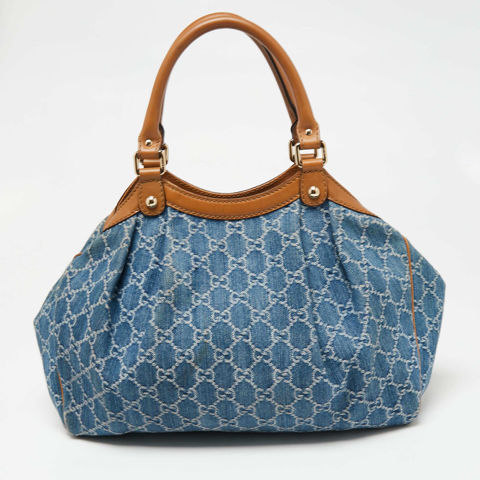 Enriched with signature details, this Sukey tote from Gucci will surely win your vote as a favorite. It comes crafted from GG denim and leather and flaunts dual handles, a branded charm, and neat pleats. Lined with fabric, its spacious interior