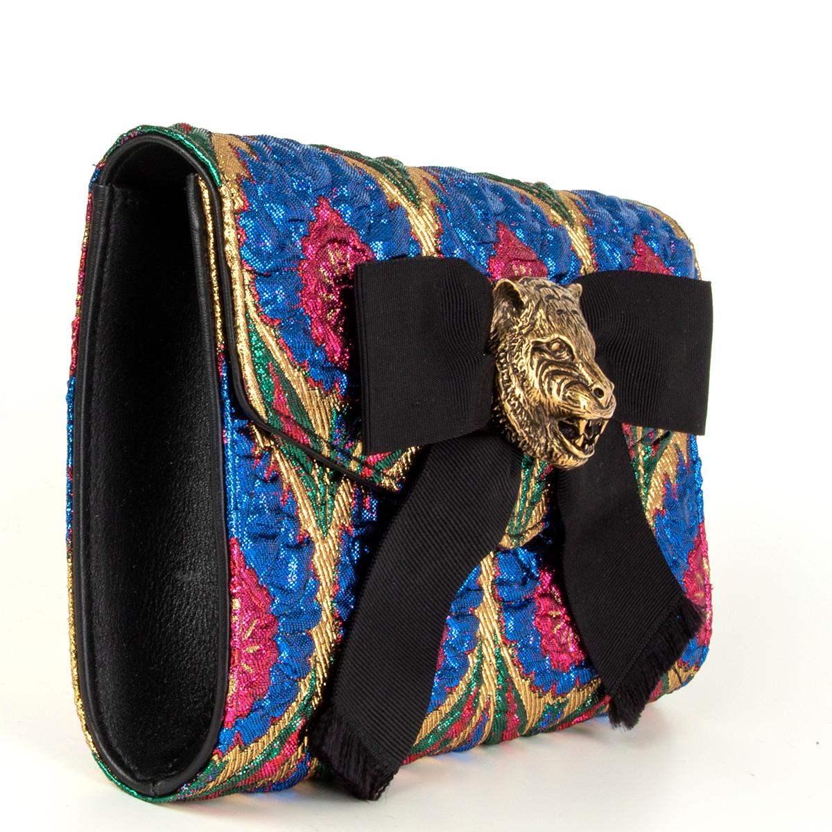 Gucci 'Animalier Broadway' clutch in pink, blue, gold and green brocade. Opens with a magnetic closure and is lined in black and tan lambskin with one open pocket against the back. Antique gold-tone feline head and black gros grain bow detail. Has