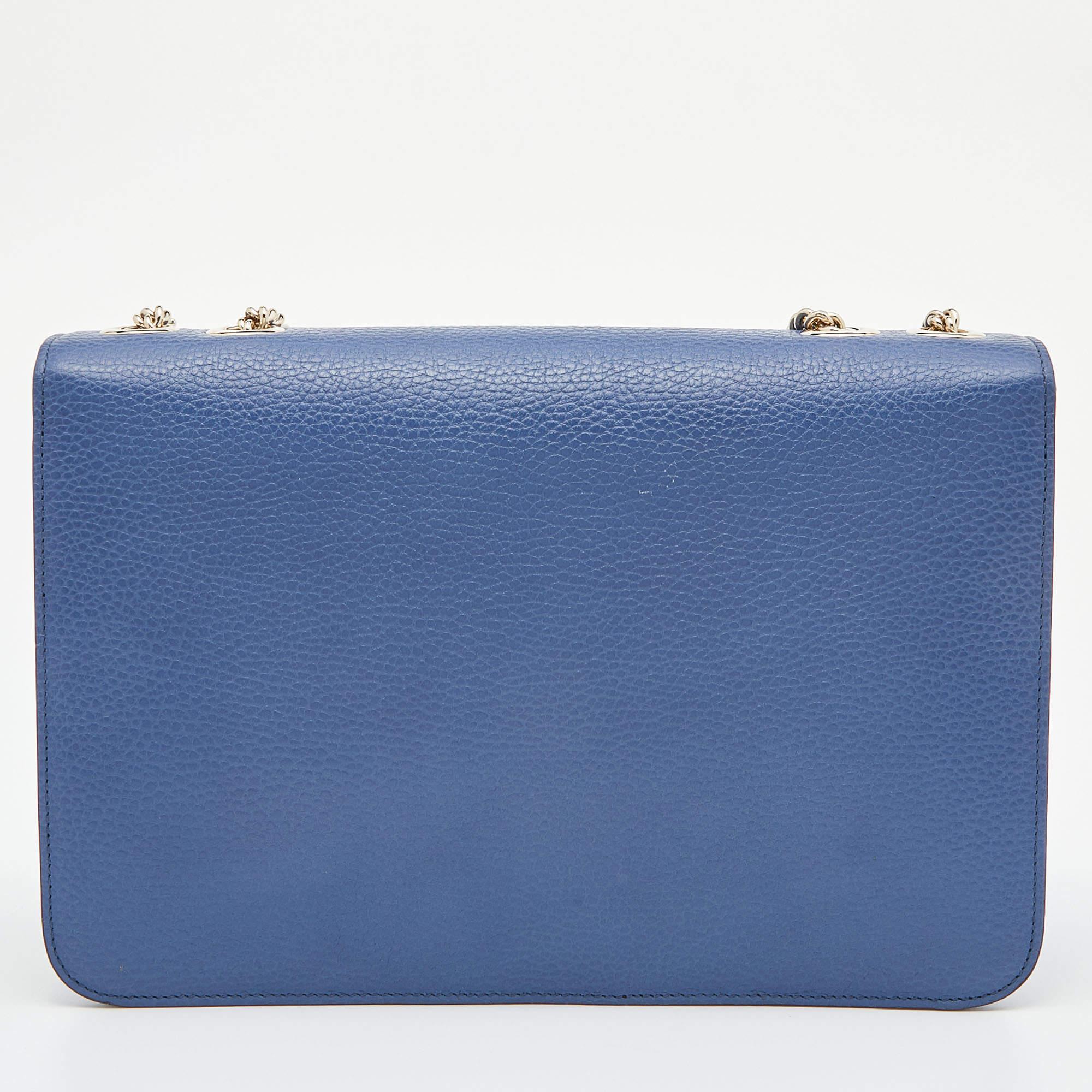 With this exquisite shoulder bag, Gucci introduces a stunning creation. Crafted from leather in a blue hue, it is styled with a flap that has the interlocking G in a gold tone. The elegant bag has a spacious interior and a slender chain strap for an