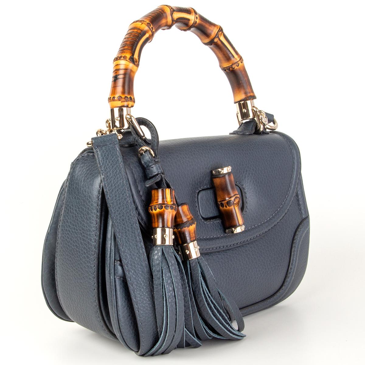 Gucci 'New Bamboo Medium' top-handle shoulder bag in navy blue grained calfskin. Opens with a bamboo turn-lock and is lined in off-white suede with one zip pocket against the back and one open pocket against the front. Comes with a detachable