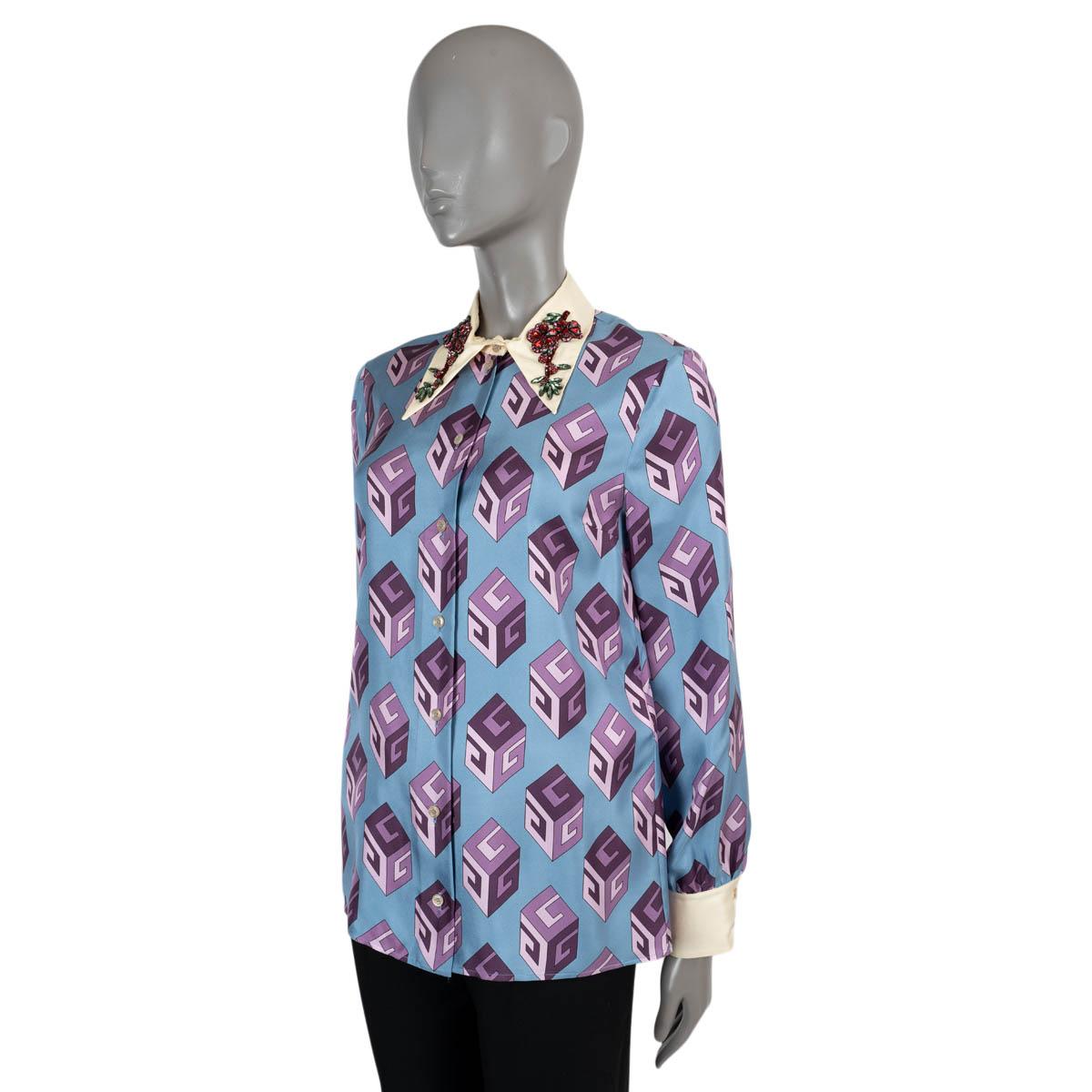100% authentic Gucci blouse in light blue silk (100%). Features G Cube print in purple, cream cuffs and pointed collar embellished with red and green floral crystals for a dazzling finish. Closes with buttons on the front. Has been worn and is in
