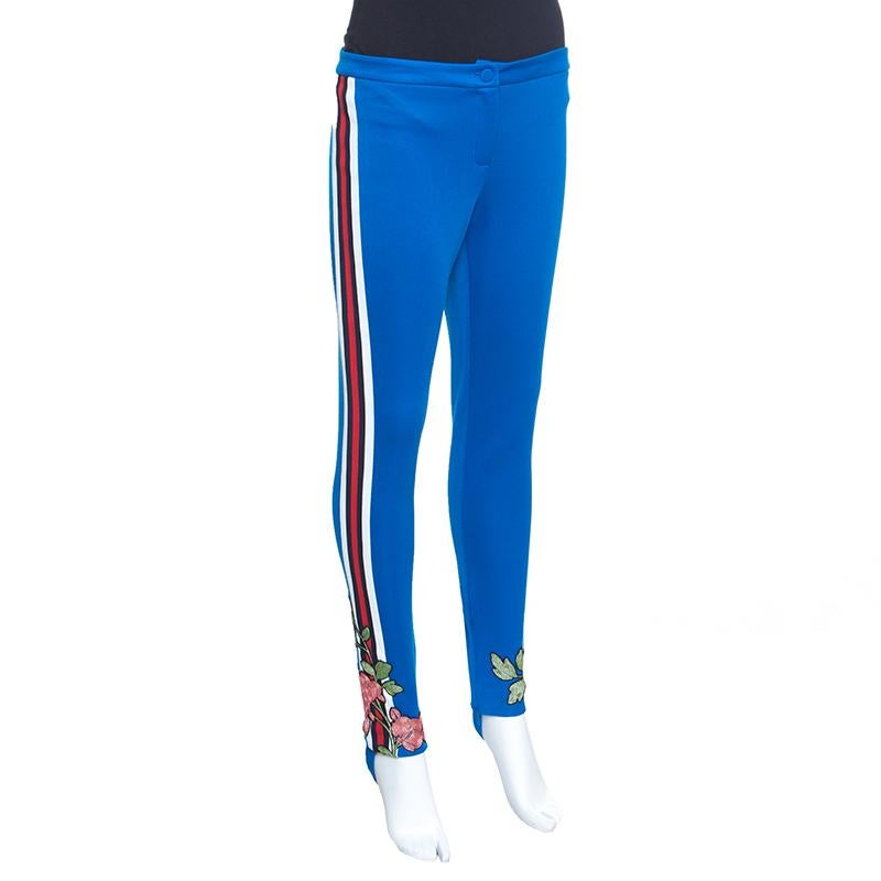 Gucci's beautifully floral embroidered track pants belong to their Spring 2016 collection. Flaunting a blue shade, these stirrup tracks are styled with stripe details on the sides and a button closure at the front. They offer a great fit and will