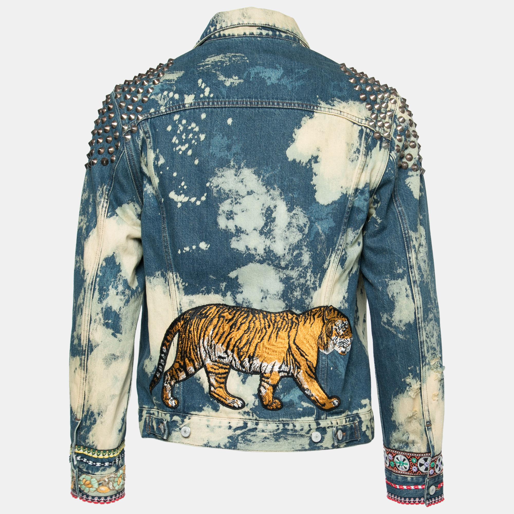 Add this Gucci jacket to your wardrobe for a stylish upgrade. It flaunts a blue, washed denim exterior with studs and an eye-catching tiger design on the back. Complete with front buttons and pockets, this exquisite jacket is nothing short of a