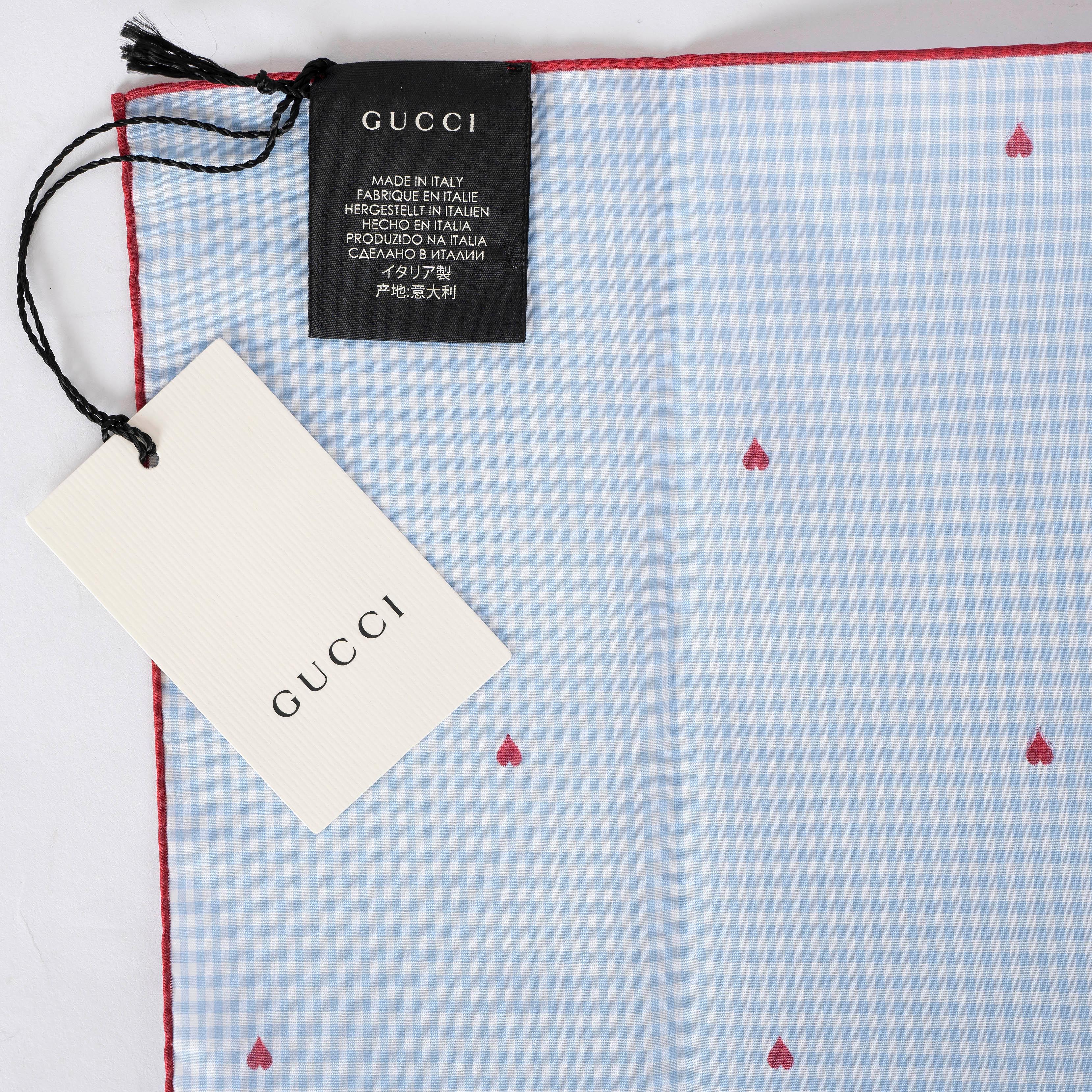 This 100% authentic Gucci pocket square scarf is crafted from light blue and white check poplin cotton (100%). It features a playful red heart print and a delicate hand-rolled edge, adding a charming touch to any ensemble with Gucci’s signature