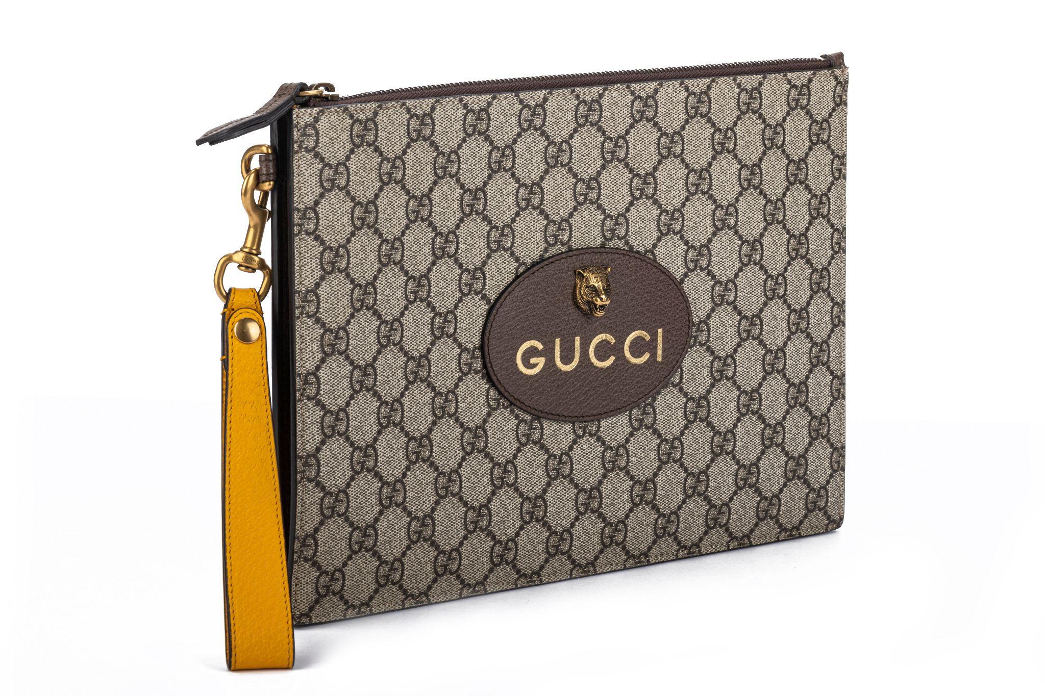 Gucci new classic brown monogram clutch with detachable yellow wristlet strap and tiger metal detail. Livret, jaquette et boîte.