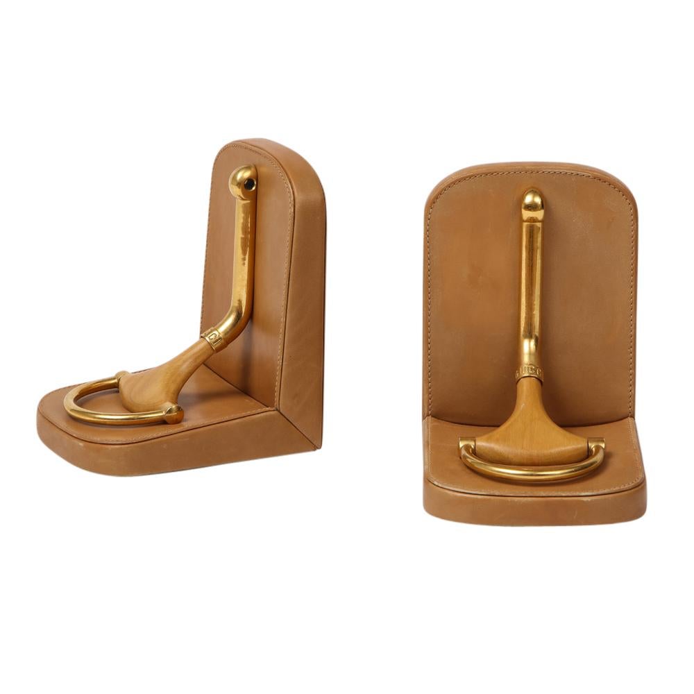 Gucci Bookends, Horsebit, Tan Leather Brass and Wood, Signed. Medium dark tan leather bookends Gucci's iconic horsebit decoration. Impressed Gucci Coat of Arms Marked Gucci on both suede undersides. Additionally marked on the brass collars of the