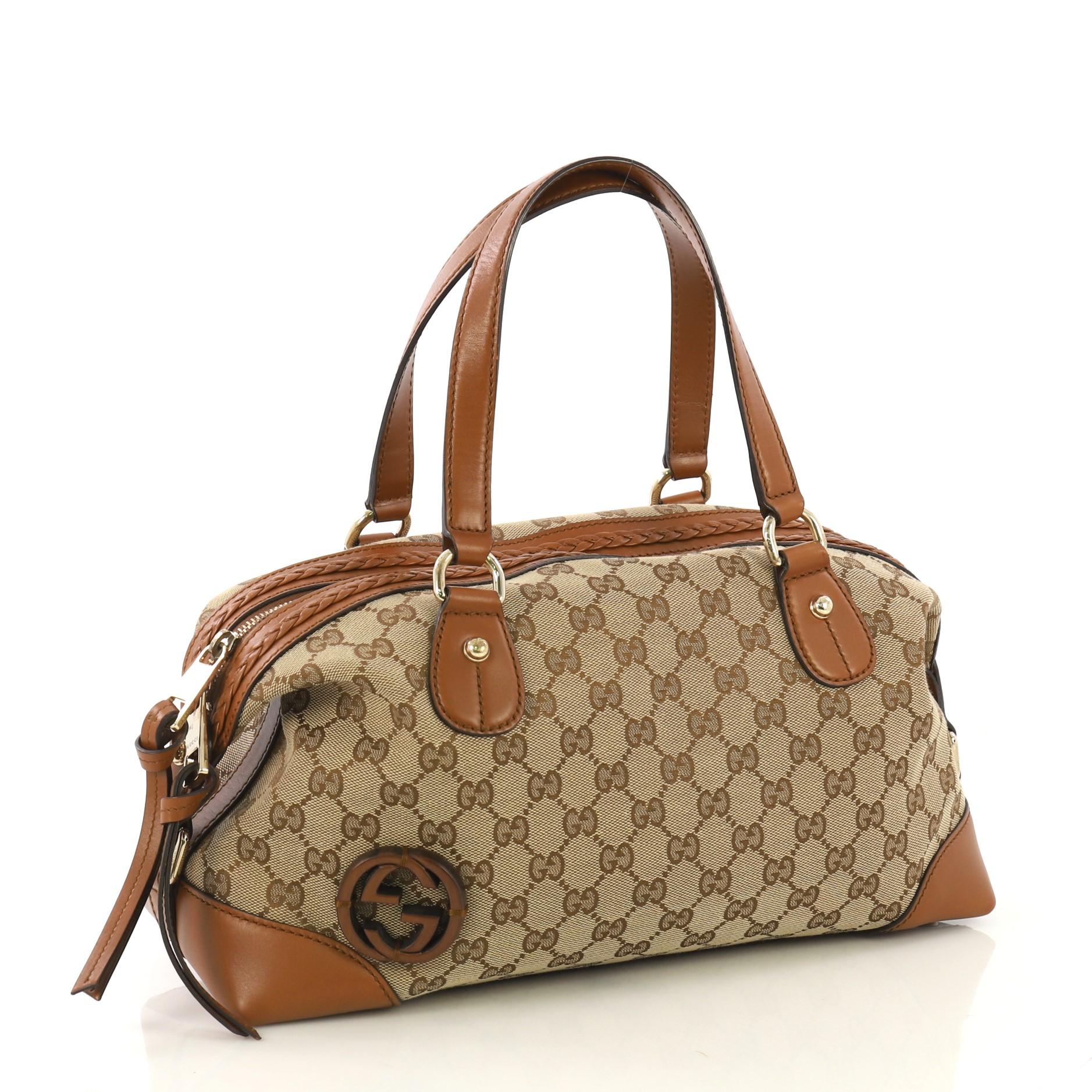 This Gucci Brick Lane Convertible Boston Bag GG Canvas Medium, crafted from beige canvas and brown leather, features dual leather handles, leather trim, and gold-tone hardware. Its zip closure opens to a beige fabric interior with side zip and slip