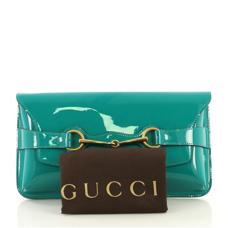 This Gucci Bright Bit Clutch Patent, crafted in green leather, features signature horsebit design and gold-tone hardware. Its slide flap closure opens to a neutral fabric interior with side zip and slip pockets. 

Estimated Retail Price: