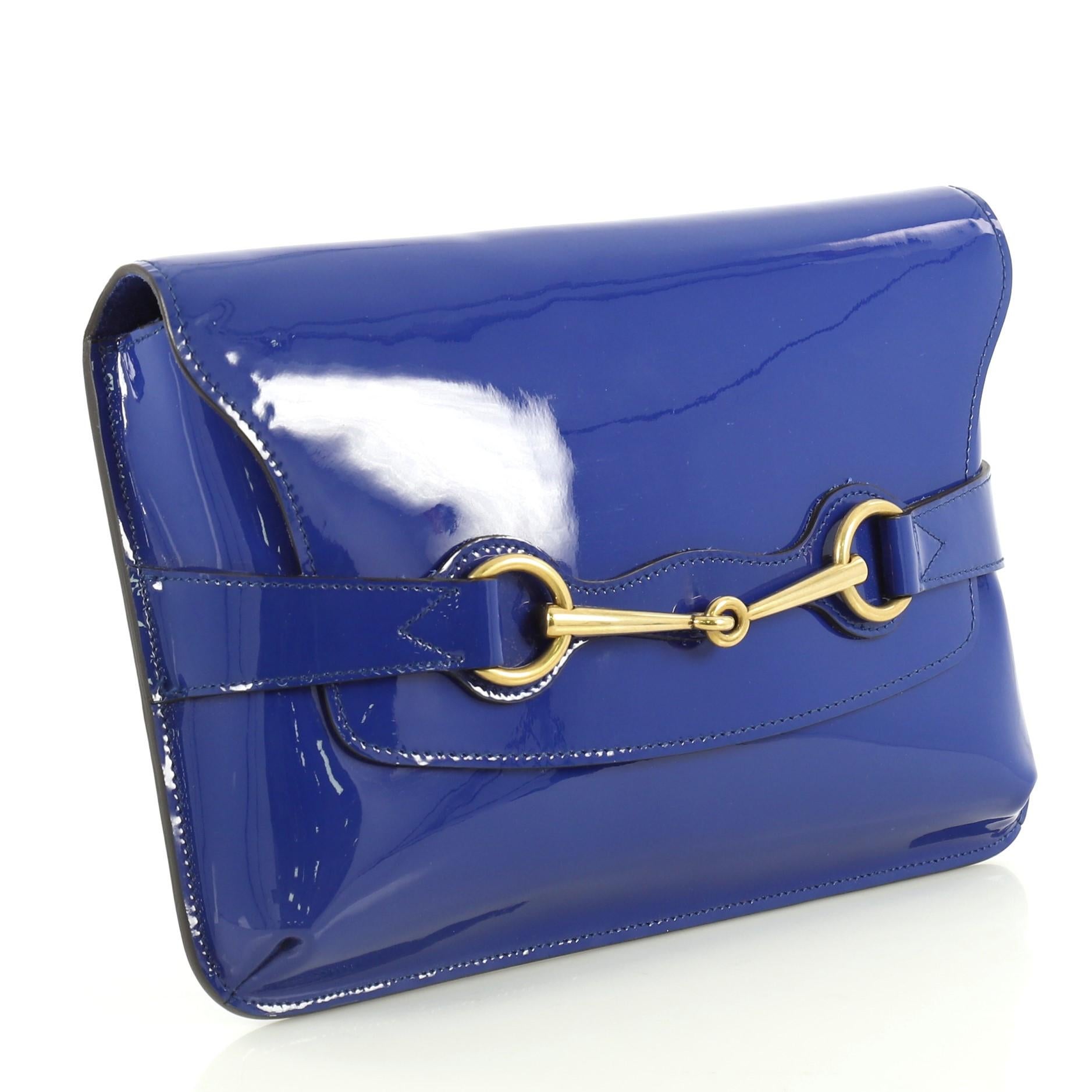 This Gucci Bright Bit Clutch Patent, crafted in blue patent leather, features signature horsebit design and aged gold-tone hardware. Its slide flap closure opens to a neutral fabric interior with side zip and slip pockets. 

Estimated Retail Price:
