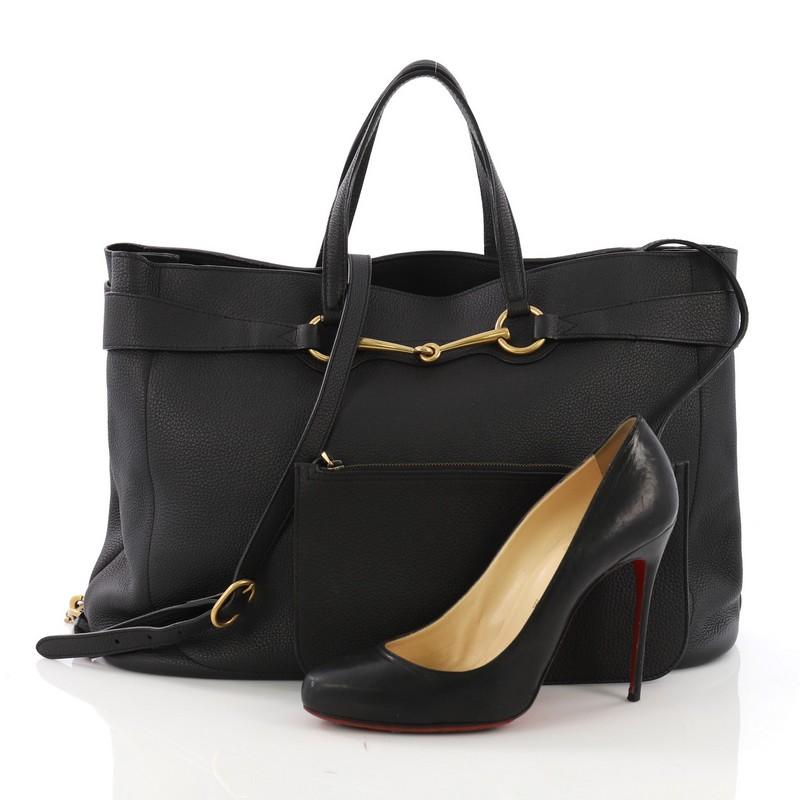This Gucci Bright Bit Convertible Tote Leather Large, crafted in black leather, features dual leather handles, signature horsebit design, side snap buttons, and aged gold-tone hardware. Its top zip closure opens to a black leather interior with side