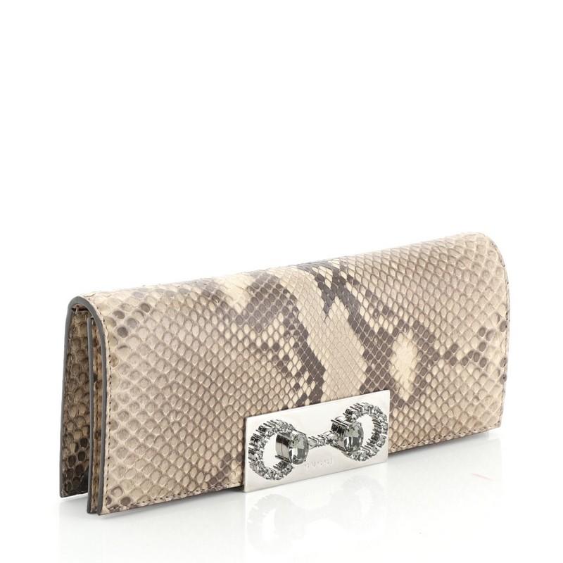 This Gucci Broadway Crystal Horsebit Clutch Python, crafted in genuine neutral python skin, features a crystal horsebit detailing and silver-tone hardware. Its snap button closure opens to a gray neutral leather interior.  This item can only be