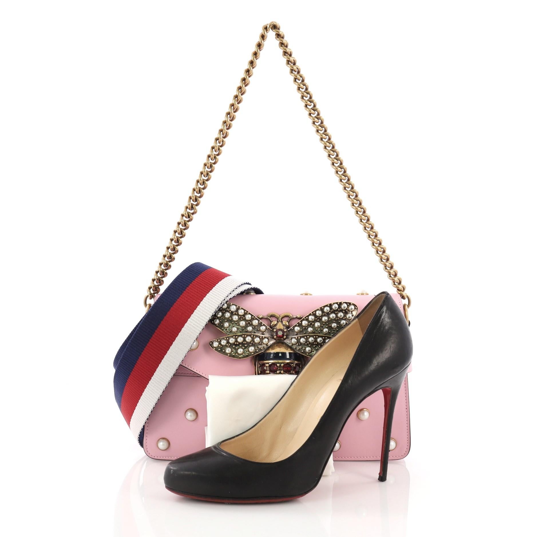 This Gucci Broadway Pearly Bee Shoulder Bag Embellished Leather Mini, crafted from pink embellished leather, features chain link strap, multiple pearl studs, metal bee design, and aged-gold tone hardware. Its magnetic snap closure opens to a nude