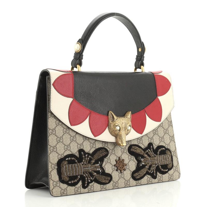 This Gucci Broche Top Handle Bag Embroidered GG Coated Canvas and Leather Medium, crafted from brown embroidered GG coated canvas with multicolor leather, features a leather top handle, chain shoulder strap and aged gold-tone hardware. Its fox head