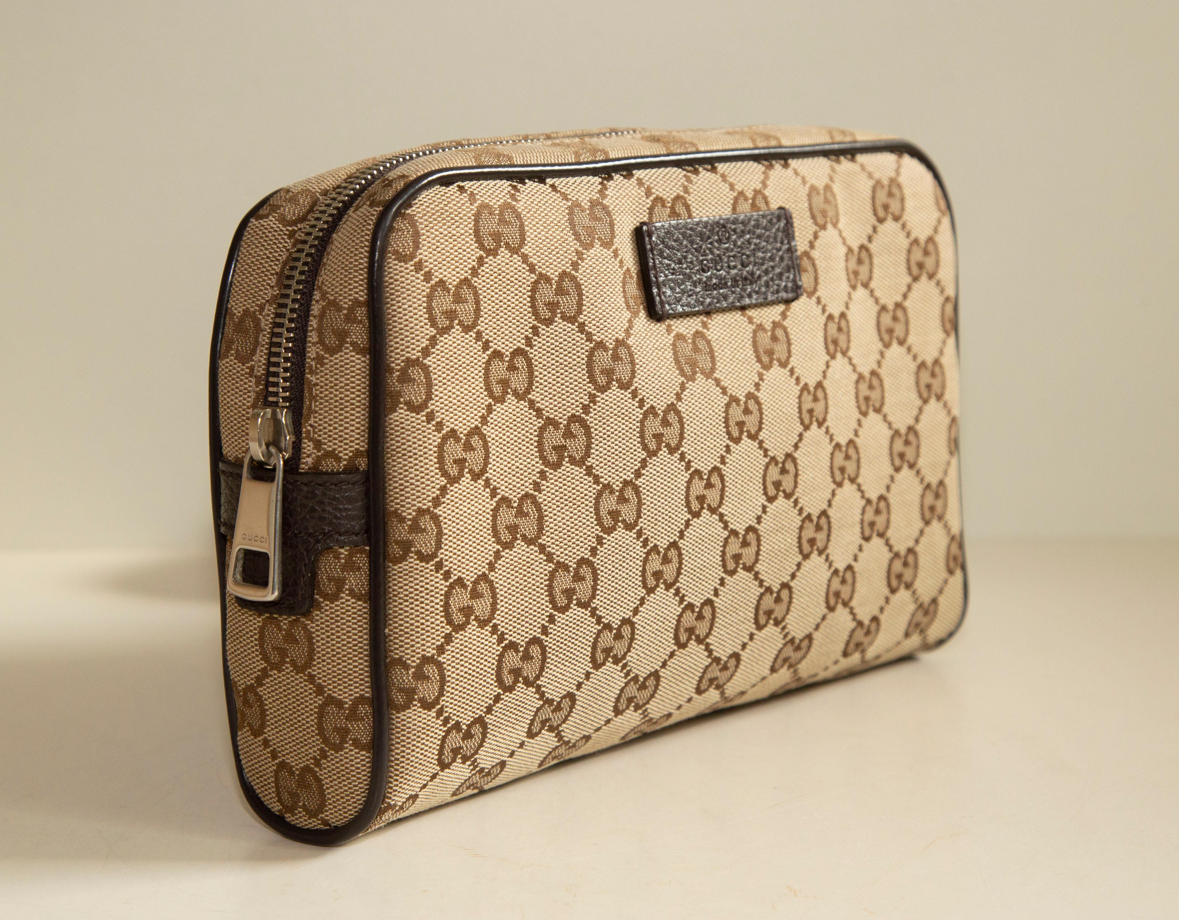 A Gucci belt bag made of classic brown and beige GG web canvas with brown leather trim. The interior is lined with brown fabric and next to the major compartment it features one side pocket. The hardware is silver toned. The canvas belt is