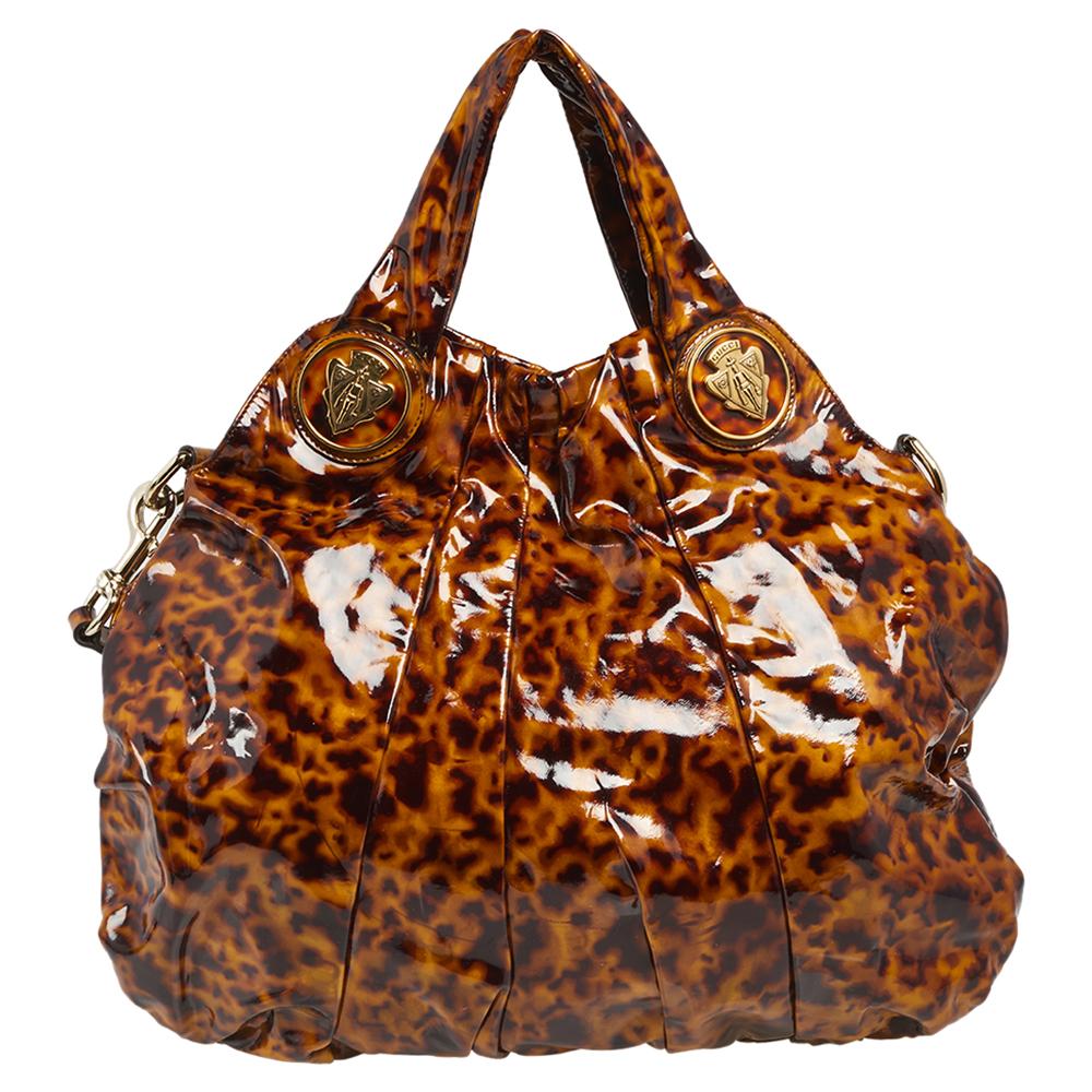 This impeccable Hysteria tote from Gucci is built for everyday use. This immaculate version features an exterior made from brown animal-print patent leather with gold-toned Hysteria motifs adorning its slouchy structure. It comes with dual handles