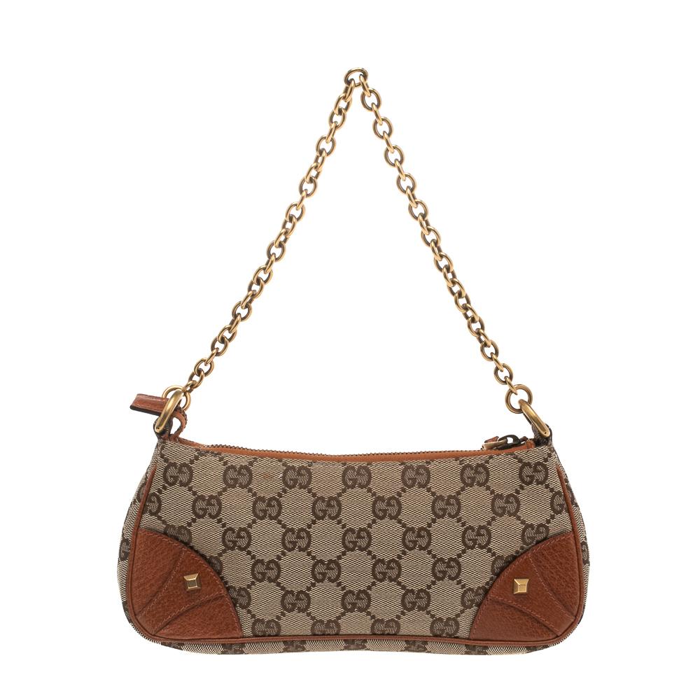 Get a winning look with this pochette bag from Gucci. Crafted from beige GG canvas the bag features four studs detailing at the corners. The insides are lined with fabric and will hold all your party essentials. The gold-tone chain strap further