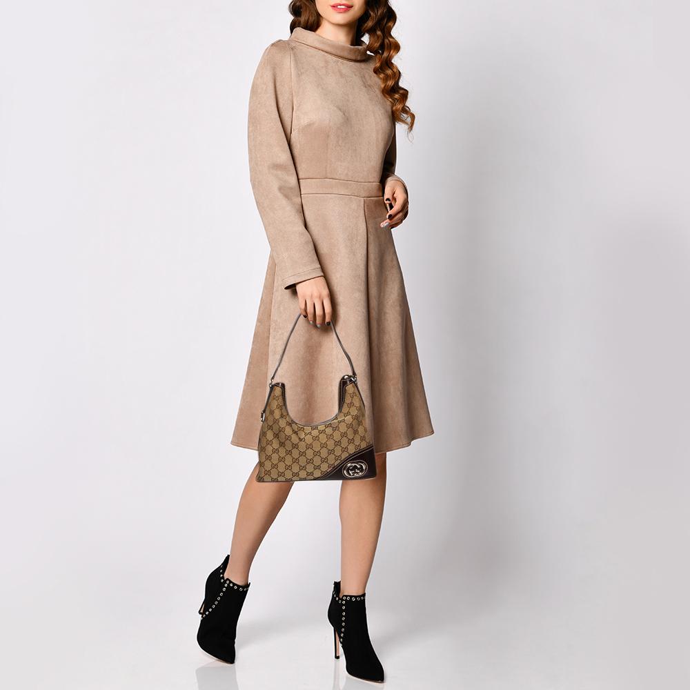 Keep your look refined and casual with this New Britt hobo by Gucci. Made from GG canvas and leather, it is adorned with a gold-tone GG logo at the corner. The creation comes with a single shoulder strap and a large interior, lined with striped