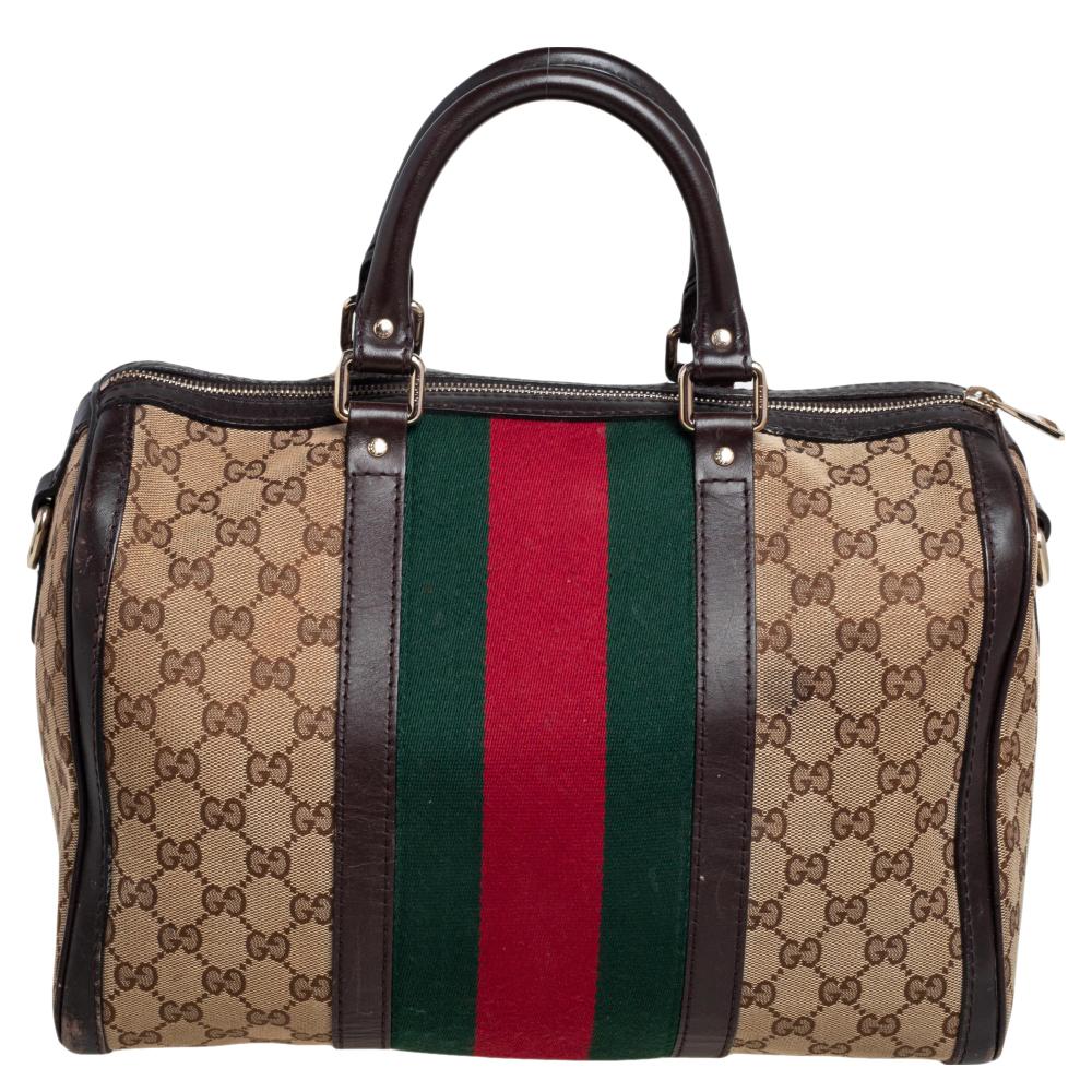 Make a luxurious addition to your designer handbag collection with this Gucci Boston bag. It exhibits a brown-beige coated canvas and leather exterior with the signature Web stripe in the center. The Vintage Web bag features a top zip closure, dual