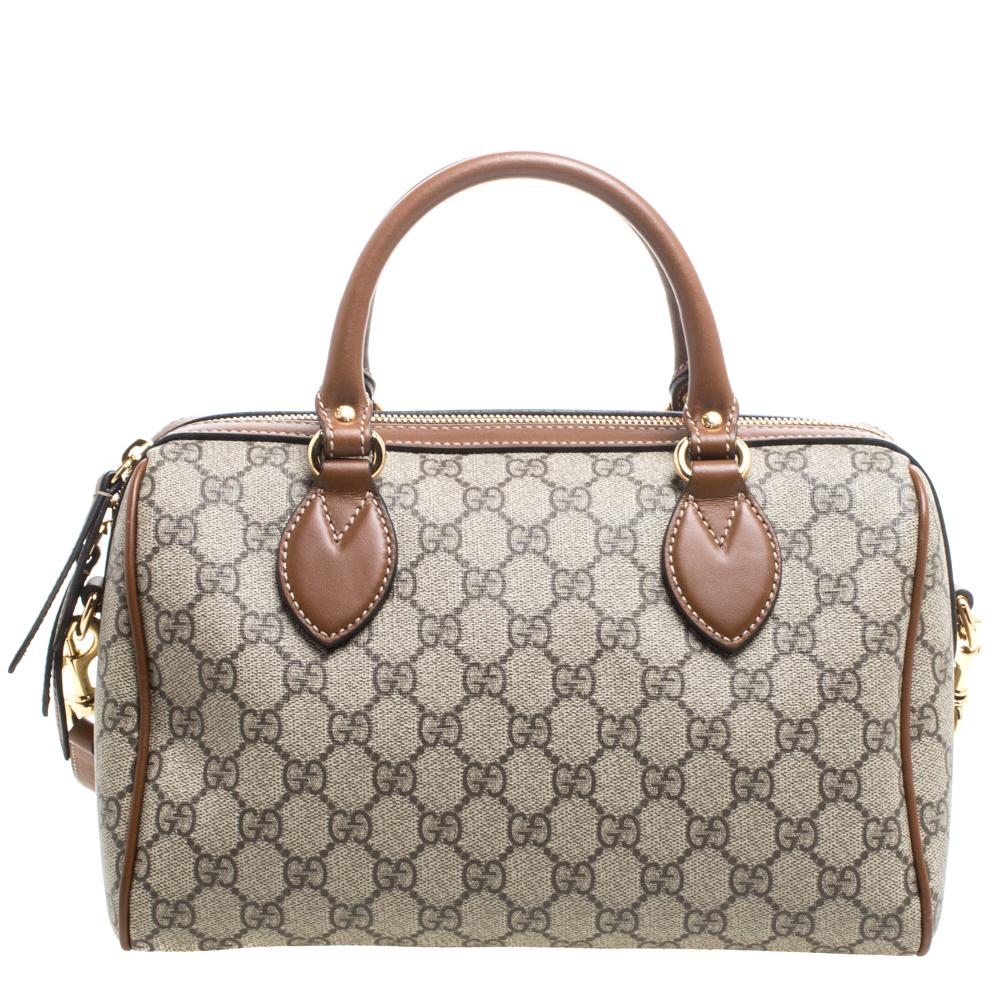 Part of Limited Edition, this Gucci Boston bag is designed in a beige coated canvas body with the iconic 'GG' detail and detailed with brown leather trims. It features a boxy silhouette and topped with two rolled top handles. It comes secured with a
