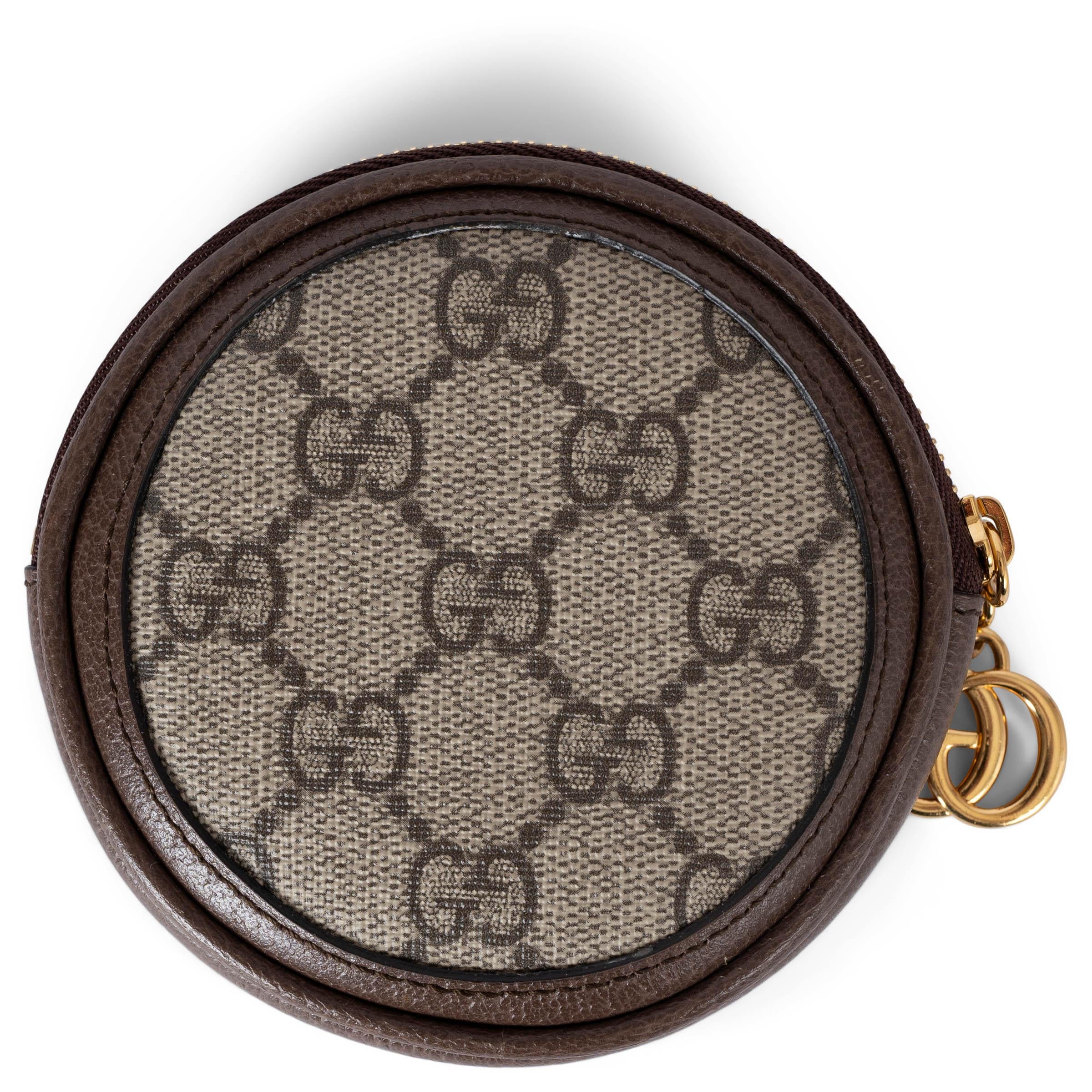 This 100% authentic Gucci Ophidia round coin wallet is crafted from beige and ebony GG Supreme canvas, accented with brown leather trims and iconic green-red web stripe. It features gold-tone hardware and closes with a zipper. The interior is lined