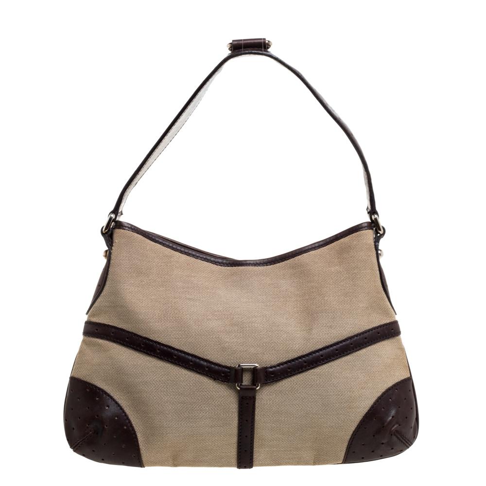 This Gucci hobo will conveniently hold all your essentials in great style. Fashioned in beige canvas and perforated leather, this classy bag comes with a top zip closure and the GG logo over the signature Web trim on the front. This hobo is ideally