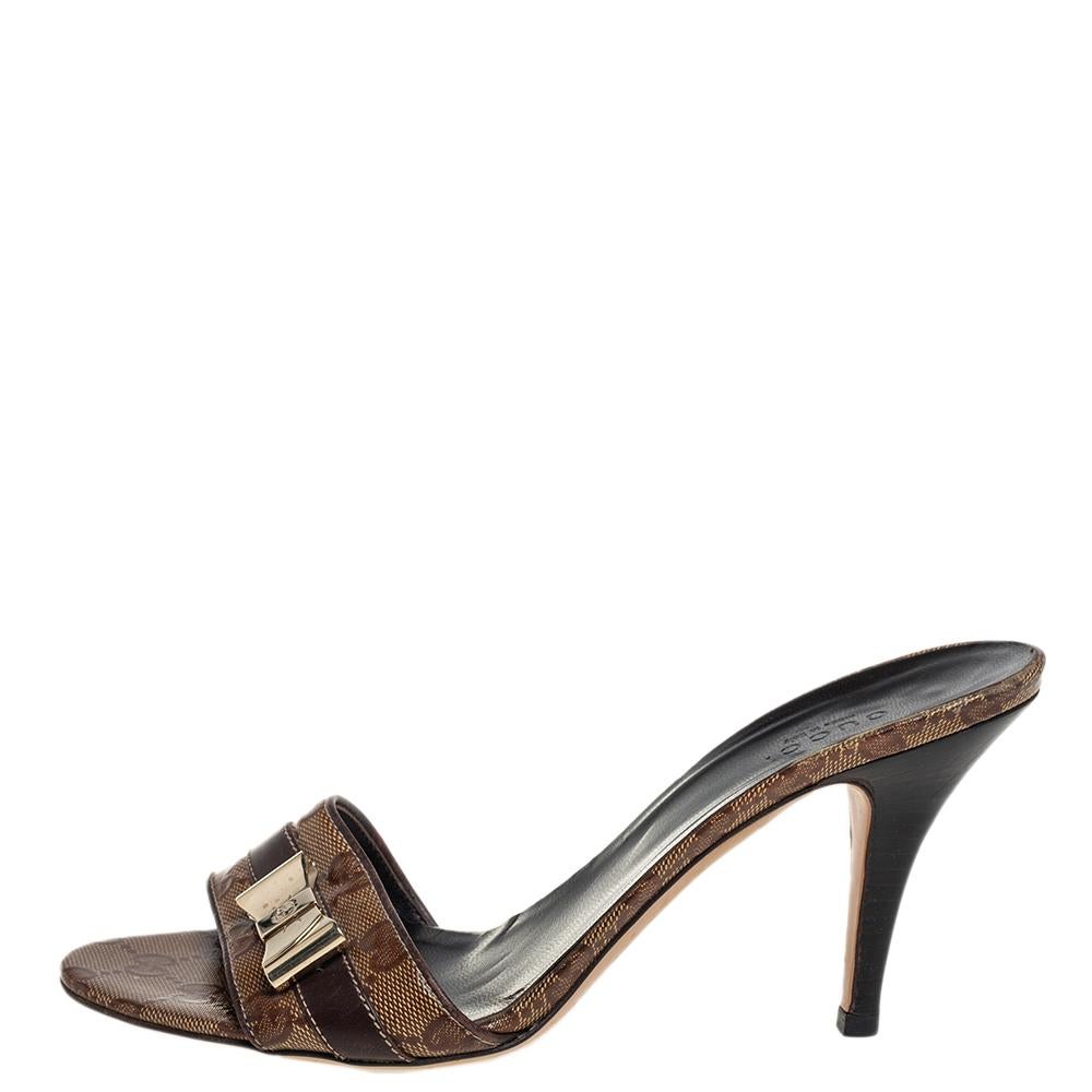 Finezza e portamento ti verranno naturali quando indosserai questo paio di sandali di Gucci. Realizzate con l'inconfondibile tela GG Crystal, le diapositive sono caratterizzate da un fiocco sul davanti e da un tacco a spillo. Le solette sono state