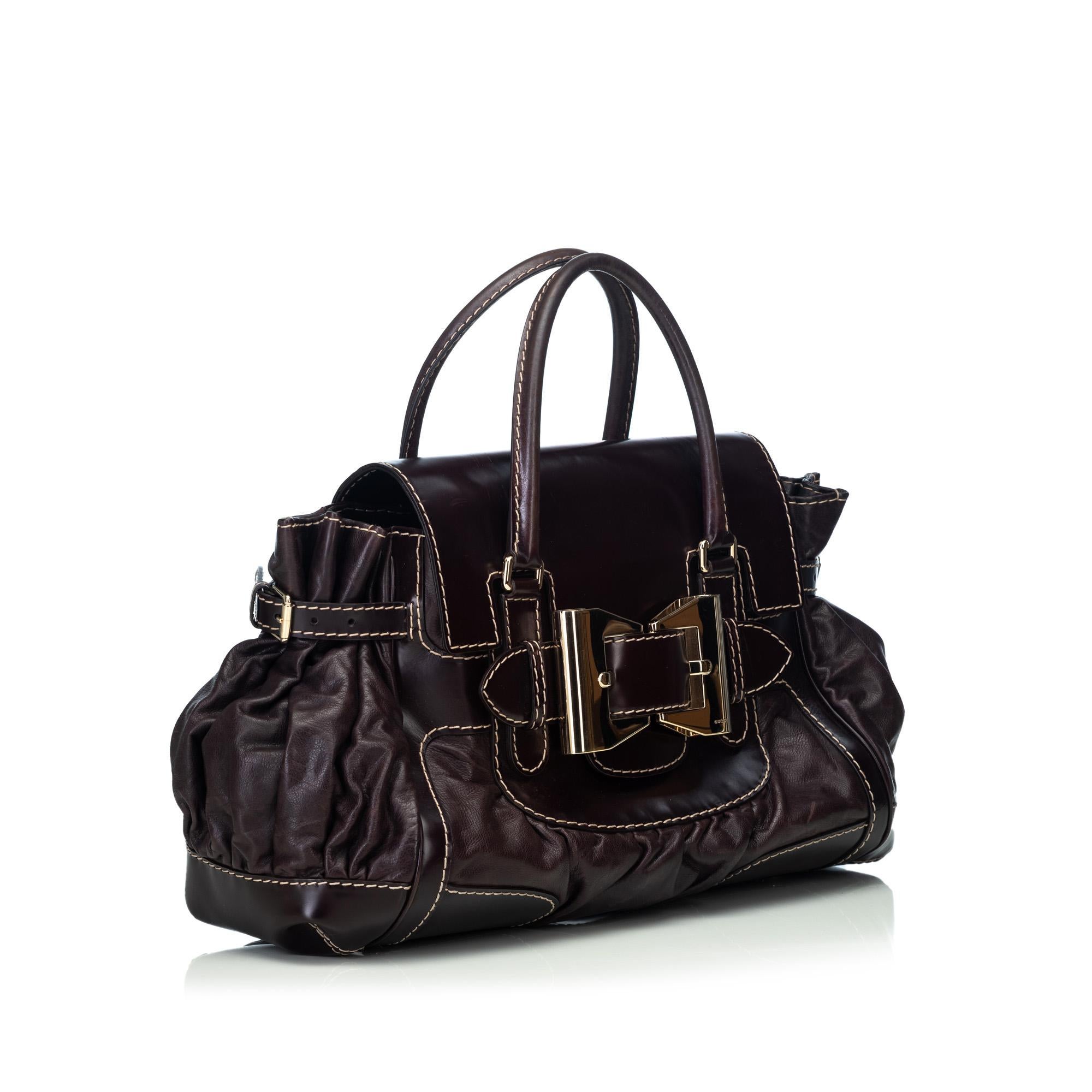 The Dialux Queen handbag features a leather body, rolled leather handles, a front flap with buckle details, an open top, and interior zip and slip pockets. It carries as B condition rating.

Inclusions: 
Dust Bag

Dimensions:
Length: 47.00 cm
Width: