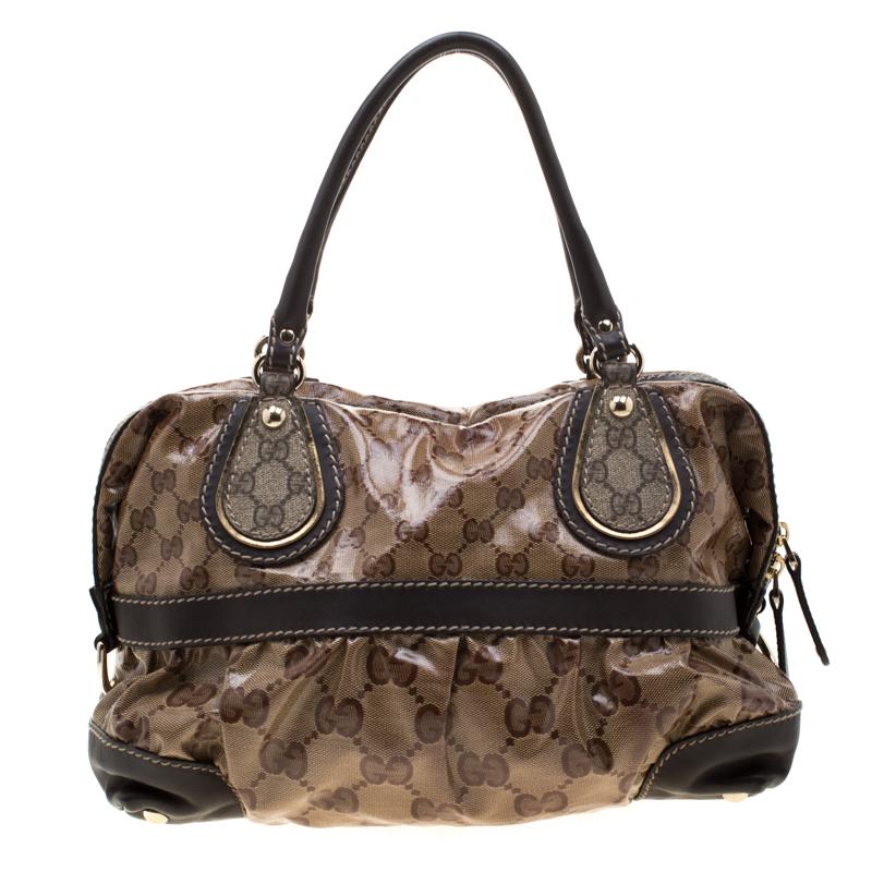 Gucci Mix tote is crafted from durable, water-resistant GG crystal-coated canvas. This bag features dual-rolled handles, brown leather trims with contrast stitching and gold-tone hardware accents and studs. The top-zip closure opens to a fabric