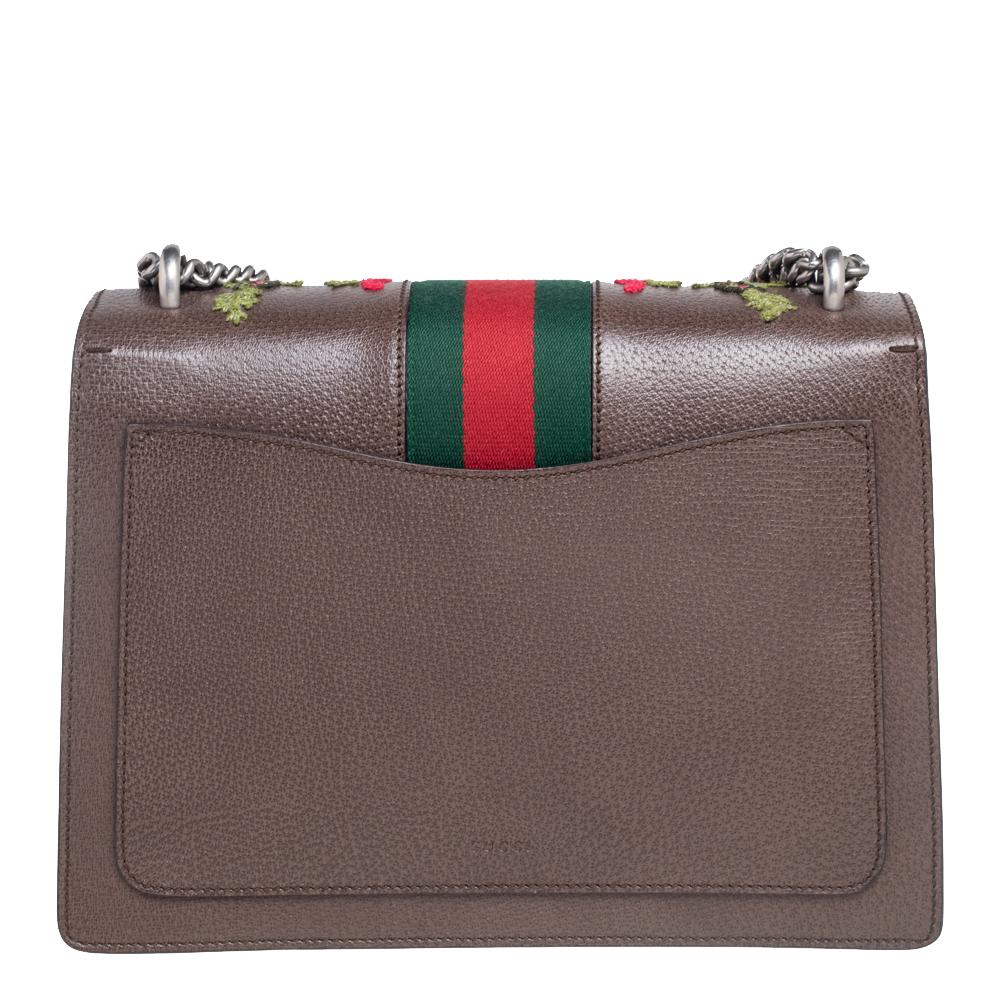 This Gucci creation has been beautifully crafted from leather in a brown shade. The exterior is adorned with floral embroideries and the flap carries tiger heads with reference to the Greek god, Dionysus and it secures canvas insides sized to