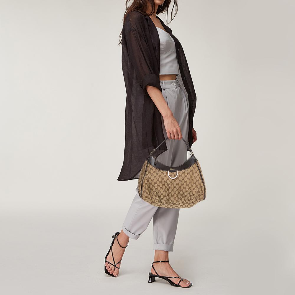 Gucci brings to you this amazing D Ring hobo that is smart and modern. Made in Italy, it is crafted from classic GG canvas and features a single top handle. The top zipper reveals a fabric-lined interior with enough space to hold all your daily