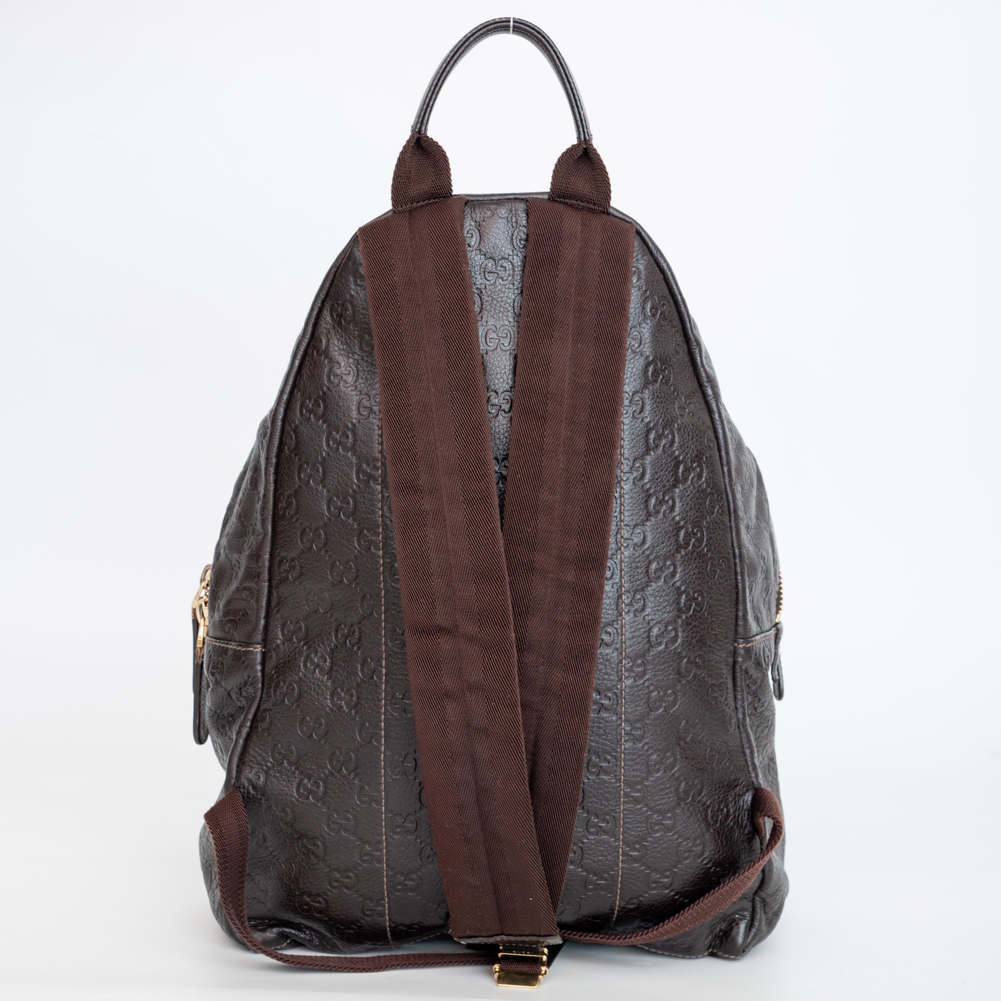 This backpack is made of Gucci Guccissima embossed leather in deep brown. The bag features adjustable padded nylon shoulder straps, a front facing zip pocket, and a primary cross-over zipper pocket. This opens to a large monogram jacquard fabric