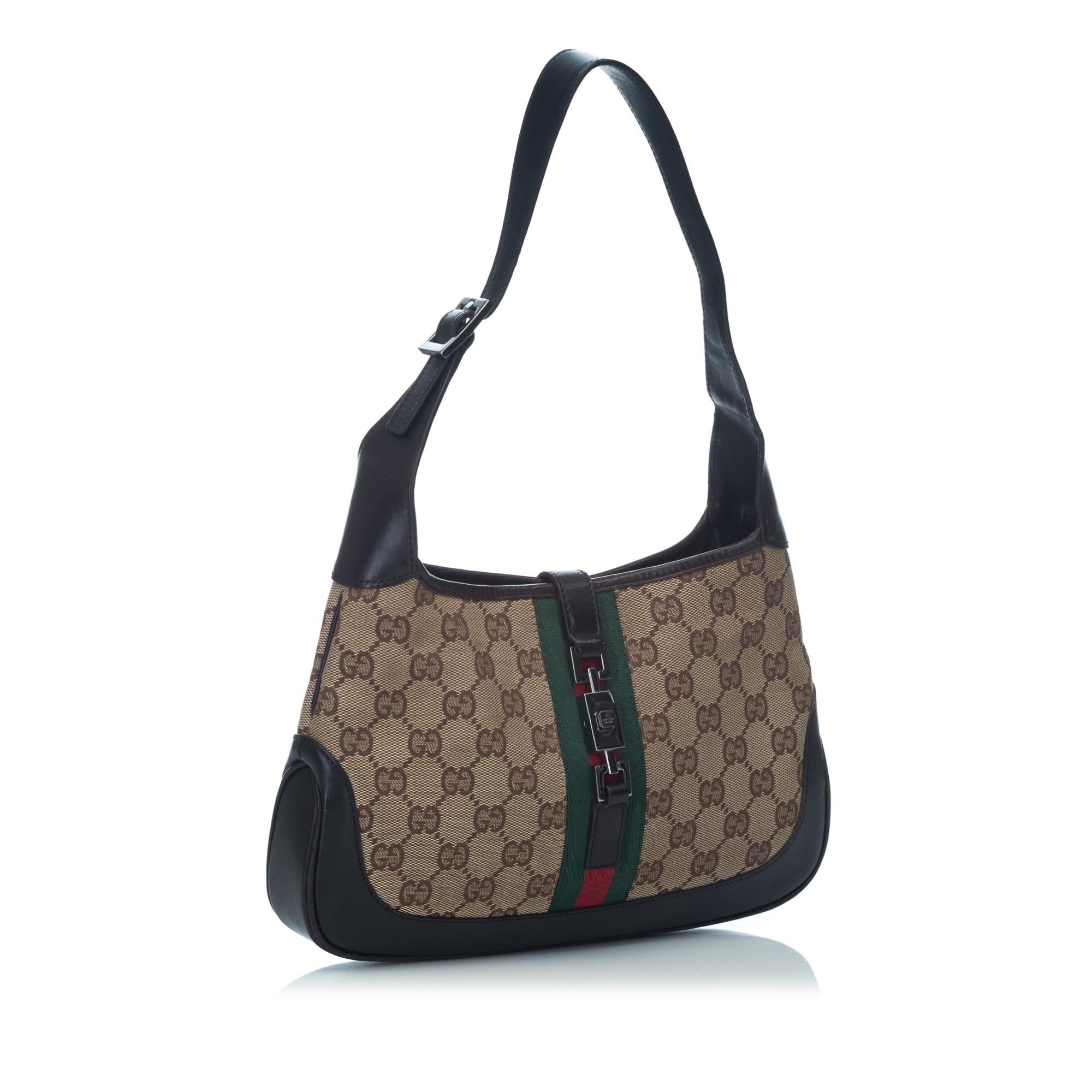 This Jackie features a canvas body with leather trim flat leather strap, open top with flat strap and push lock closure, and interior zip pocket. It carries as B+ condition rating.

Inclusions: 
This item does not come with