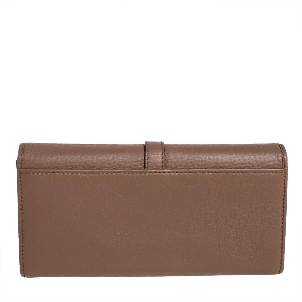Crafted from leather, this gorgeous wallet from Gucci carries a brown exterior. The slender flap is accented with a gold-tone D-ring engraved with the brand's name that opens to a leather and nylon interior equipped with multiple slots and