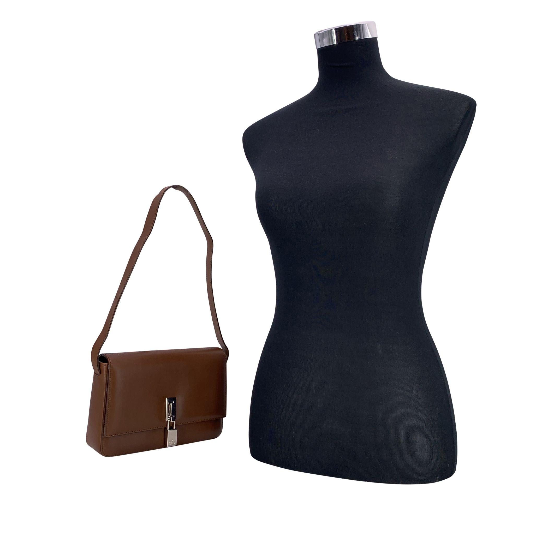 Raffinata e senza tempo, questa borsa a tracolla Gucci Box cattura l'eleganza e la struttura del design classico di Gucci. Realizzata in pelle marrone liscia, presenta una chiusura con patta accentuata da un lucchetto argentato a forma di fibbia, un