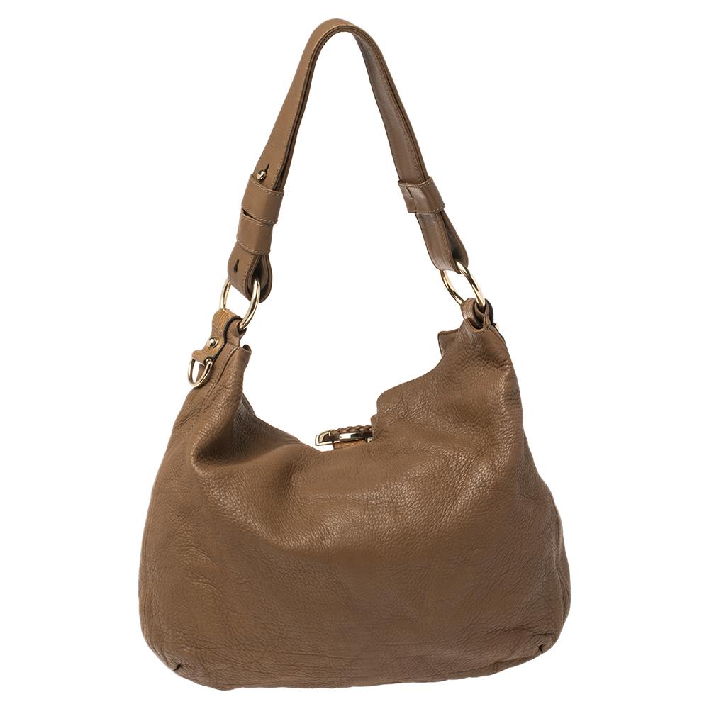 Crafted from brown leather, this Gucci creation is designed in a conventional hobo bag shape. It has a braided strap as well as an adjustable handle with gold-toned hardware. The signature G sits prominently at the center. Made in Italy, the