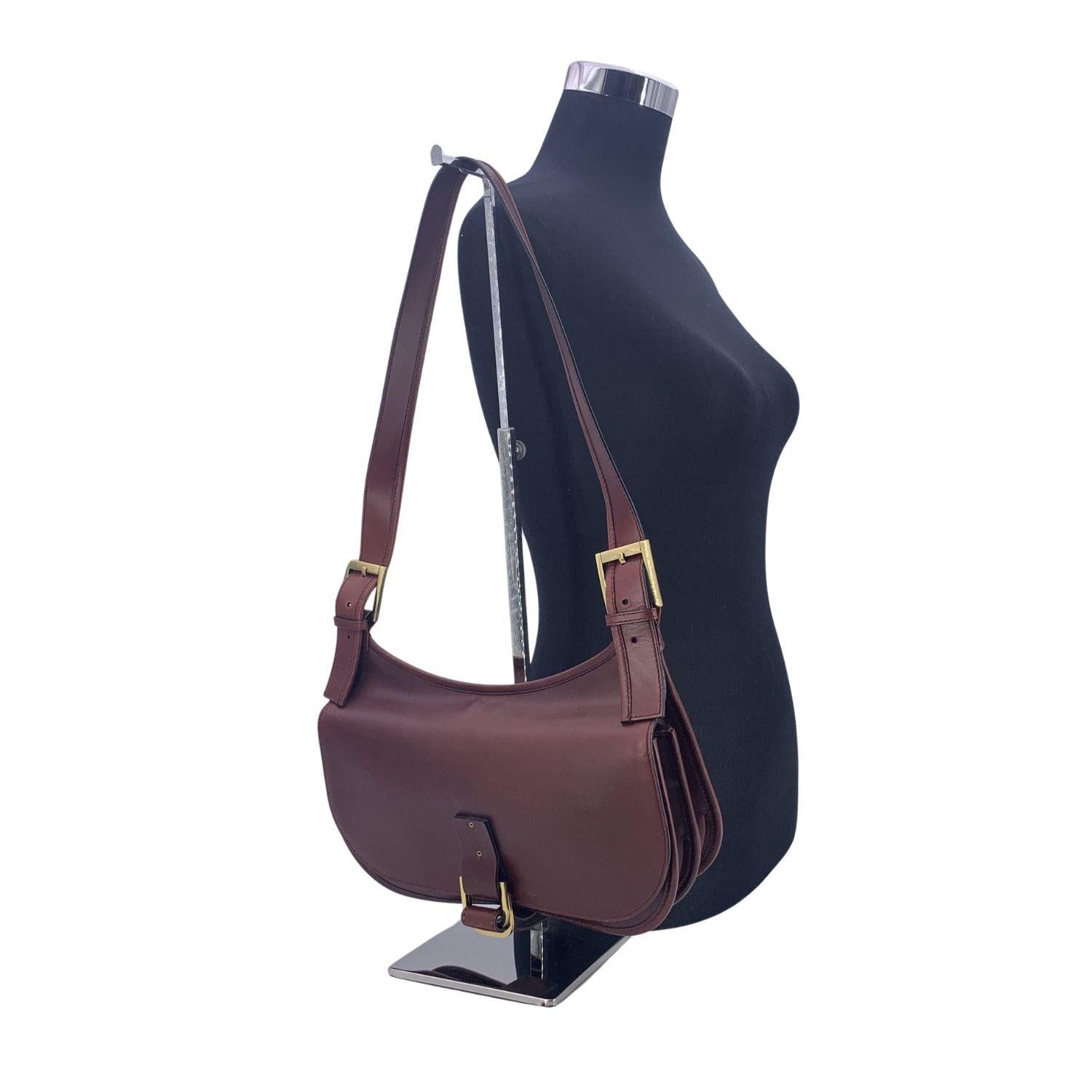 Gucci vintage brown leather saddle shoulder bag, with hobo design. Flap closure. Gold metal hardware. Black fabric lining. 2 main compartments inside. 1 side zip pocket inside. 'Gucci - Made in Italy' tag inside (with serial number on its reverse).