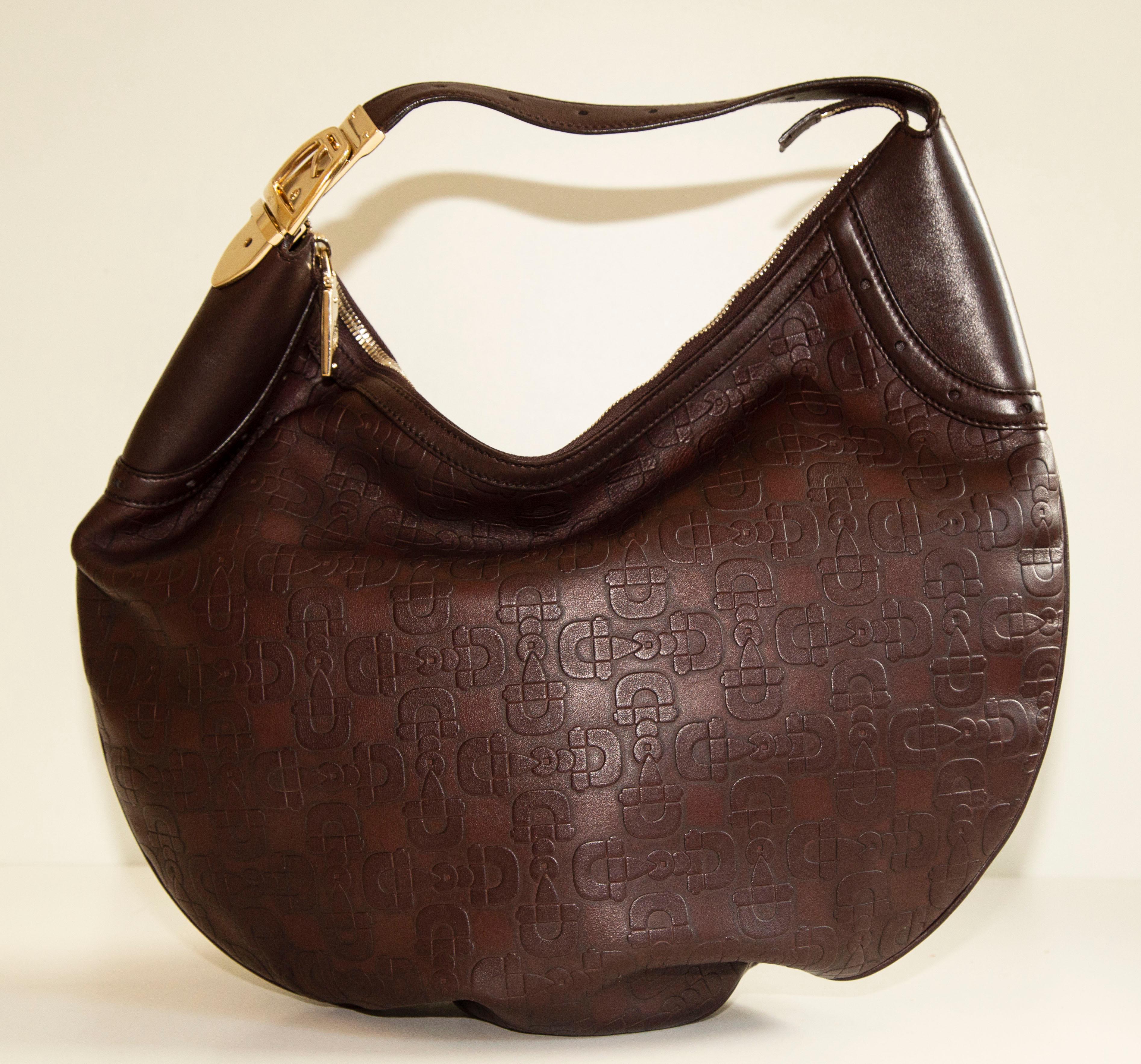 A vintage, genuine Gucci brown/dark bordeaux leather horsebit embossed buckle hobo shoulder bag with gold-tone hardware. The interior is lined with dark brown fabric and it consists of one central compartment and one side pocket with a zipper. The