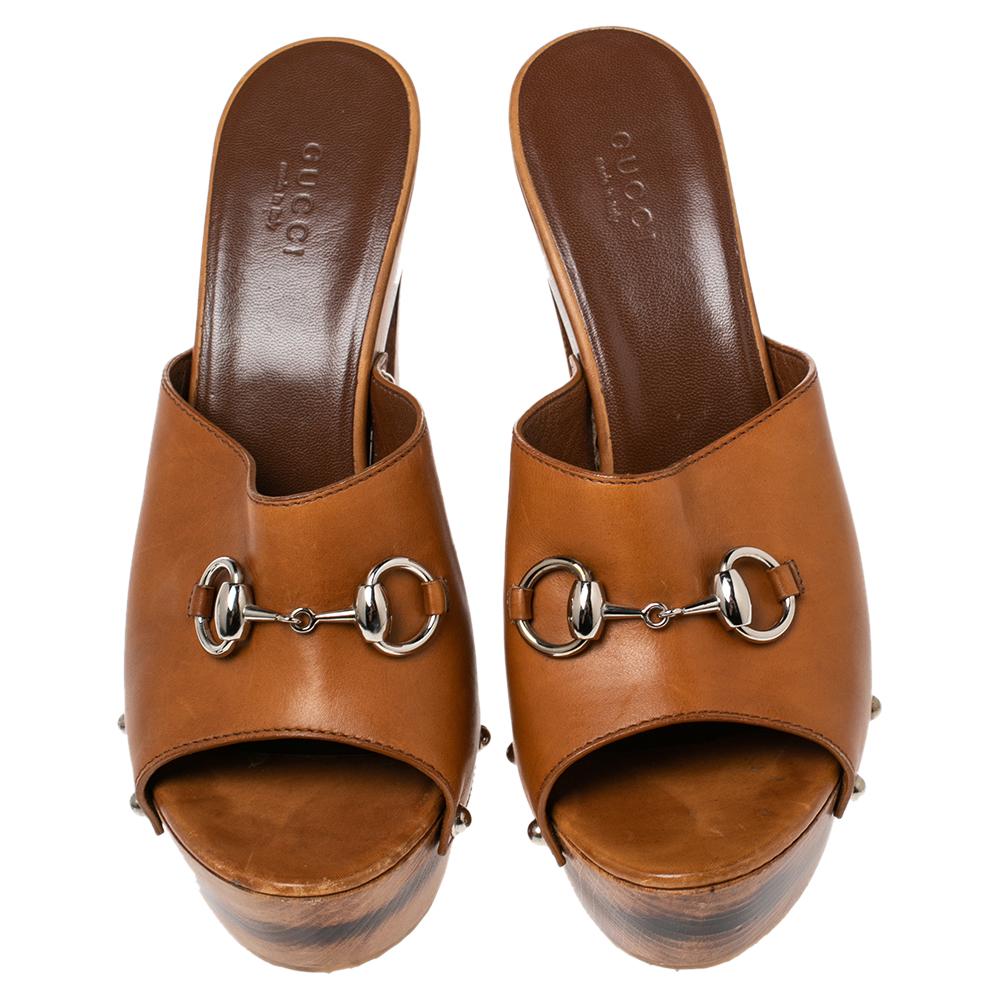 Embrace comfortable style with these clogs from Gucci! They carry a brown exterior made from leather and are designed with the iconic Horsebit detail on the uppers. They are complete with wooden platforms and 14.5 cm wooden heels.

Includes: