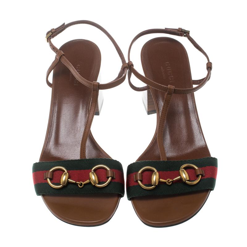 Styled with perfection, this brown Gucci number is crafted in leather as a T-strap and completed with ankle fastenings. The signature web strap on the front accented with Horsebit detail in gold-tone, coupled with low heels makes it a pair that's