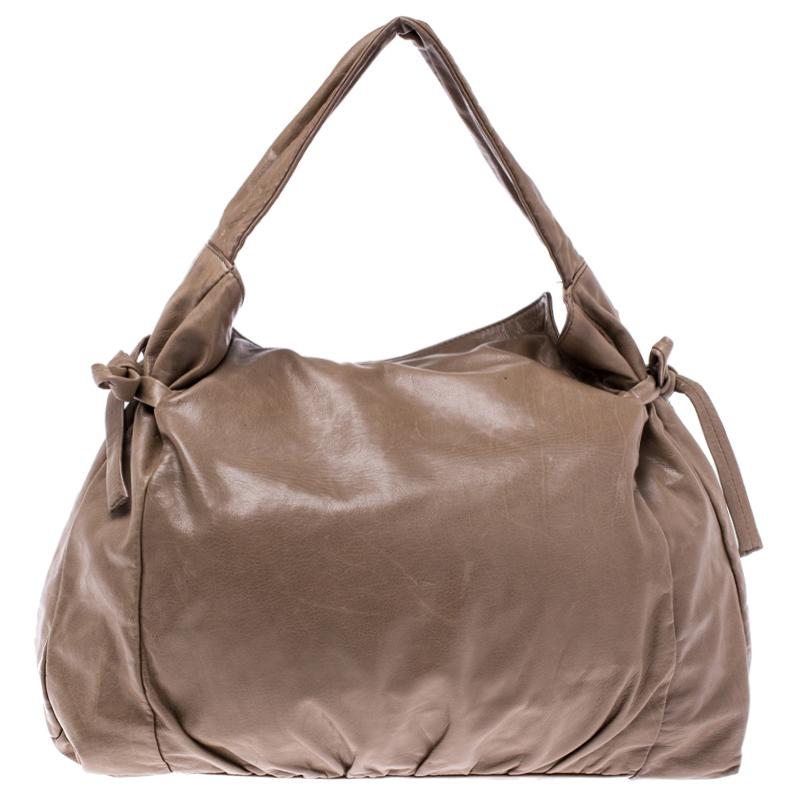 This Gucci hobo is built for everyday use. Crafted from brown leather, it has ties on the sides and a single handle for you to parade it. The nylon insides are spacious and the hobo is complete with the signature emblem on the front.

Includes: The