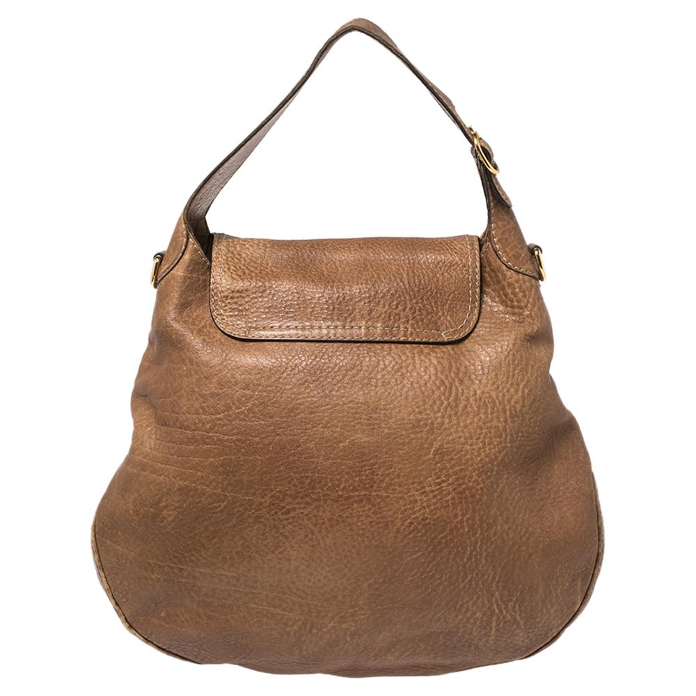 This New Pelham hobo bag from Gucci epitomizes the modern-elegant essence of the label. With the brown leather exterior adorned with Horsebit details, it comes with a handle & a long braided shoulder strap that’s pretty and comfortable. Its roomy