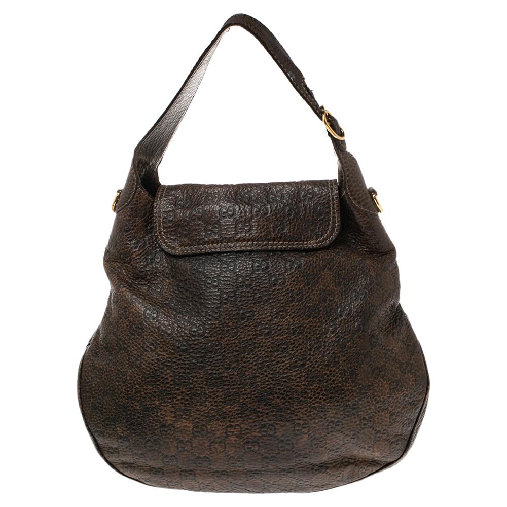 This gorgeous Gucci handbag is a throwback on the rugged, rustic Western look. The horse-bit details add to the vintage look of the brown leather. The fabric lining has one zippered pocket while an exterior pocket is placed under the flap. The bag