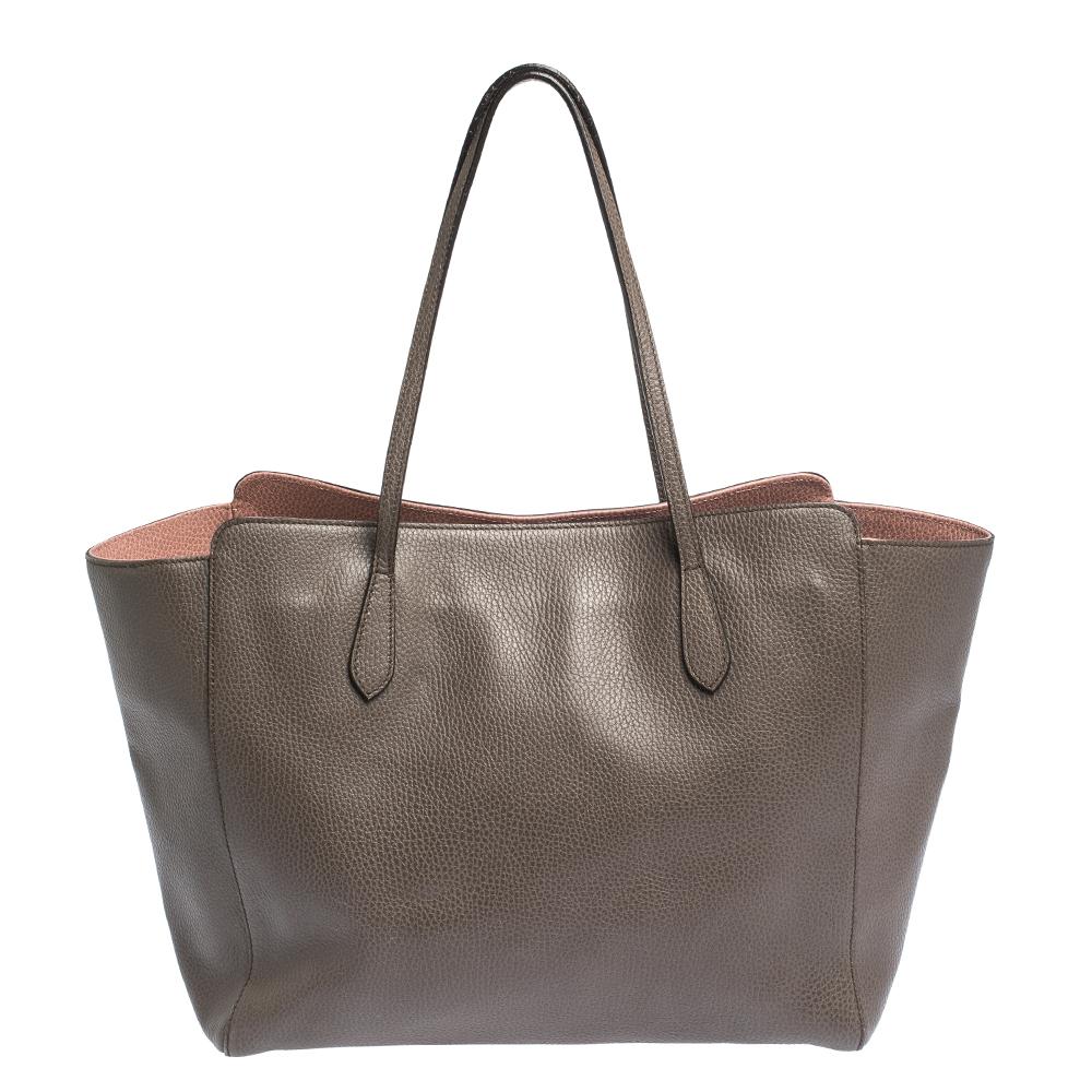 High in appeal and style, this Swing shopper tote is a Gucci creation. It has been crafted from quality leather in Italy and shaped to exude class and luxury. The brown-hued bag comes with two handles, a spacious fabric interior, and the brand label
